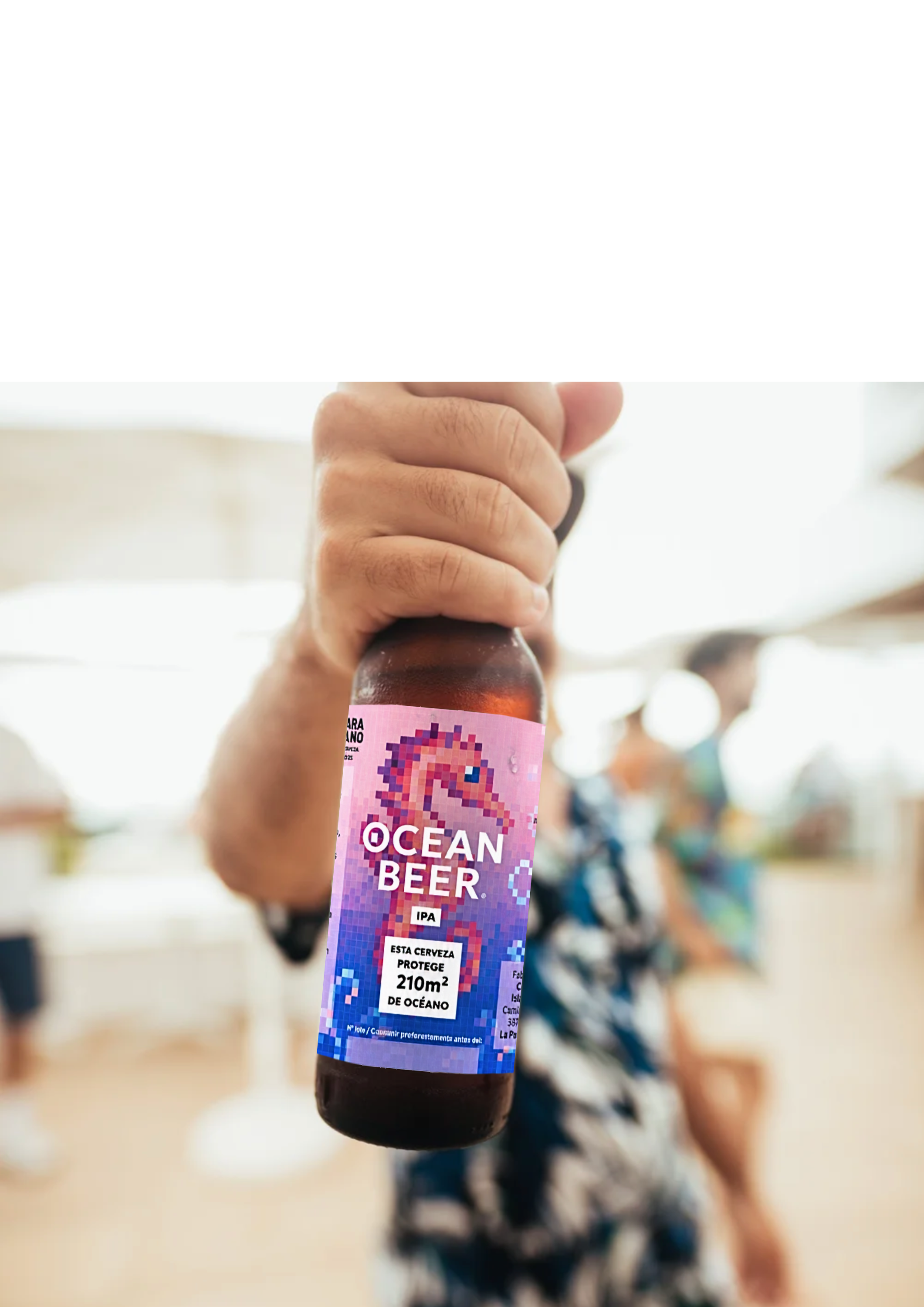 A bottle of ocean beer and a glass of beer on a wooden table with a shelf of bottles in the background.