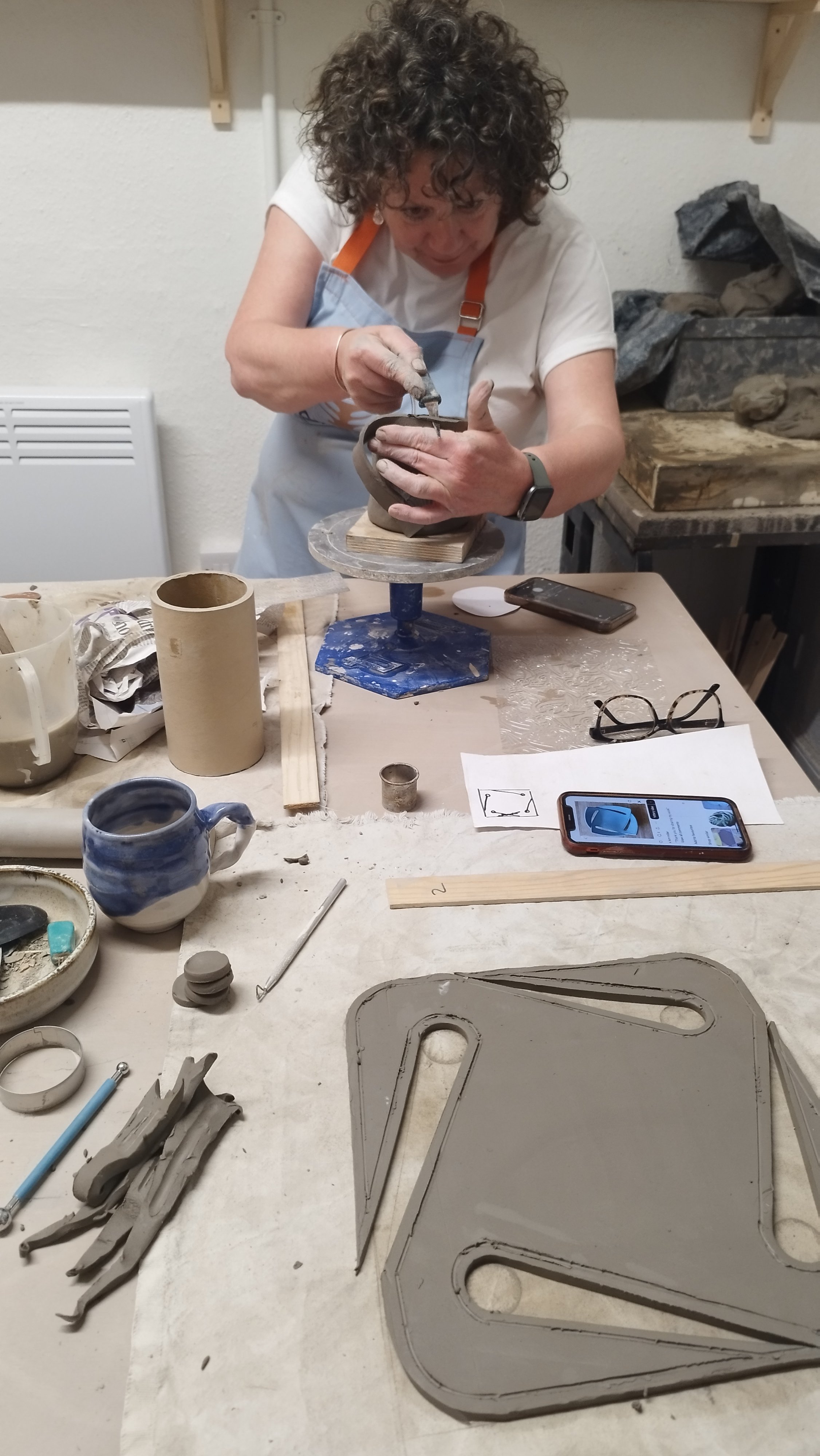Person sculpting clay with tools on a workbench