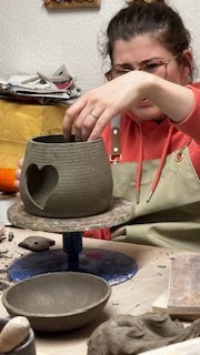 Person crafting pottery with heart-shaped cutout
