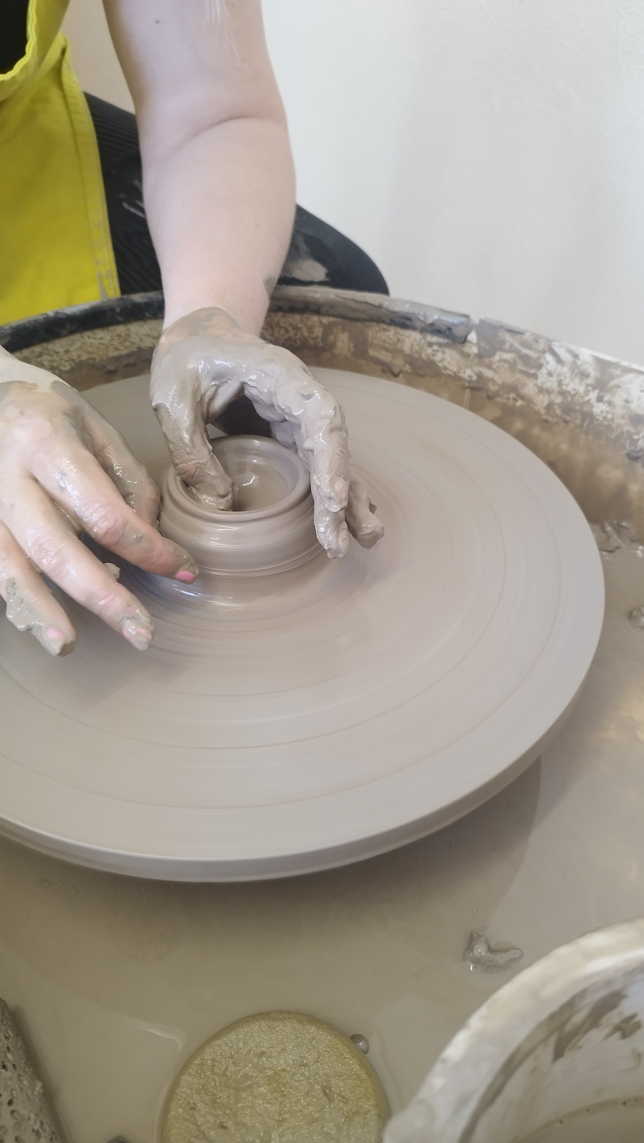 Hands shaping clay on a pottery wheel