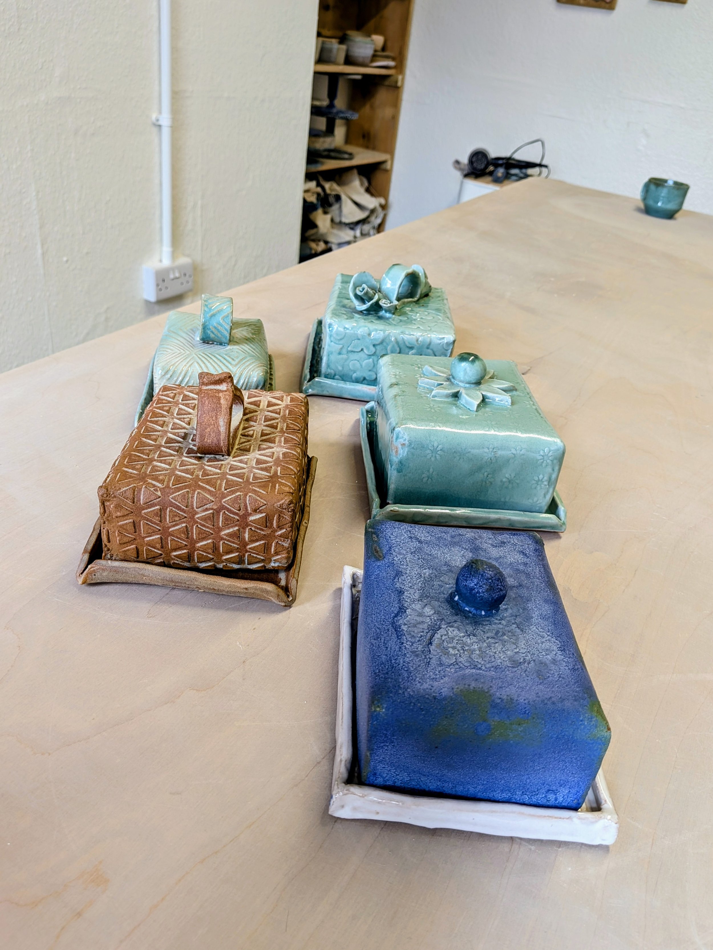 Ceramic butter dishes with textured designs and different colors on a table