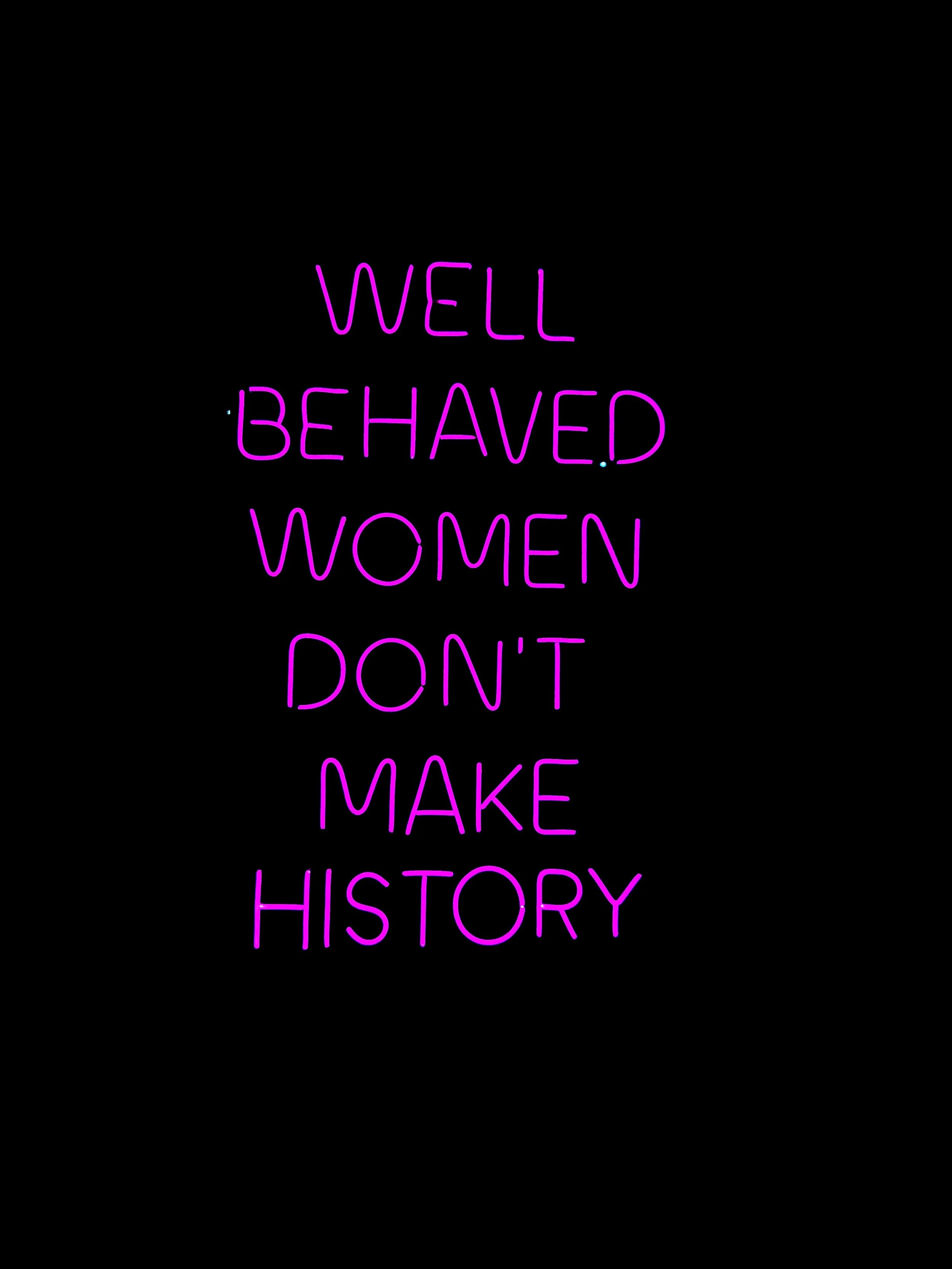 "Well behaved women don't make history" in pink neon letters on a black background.