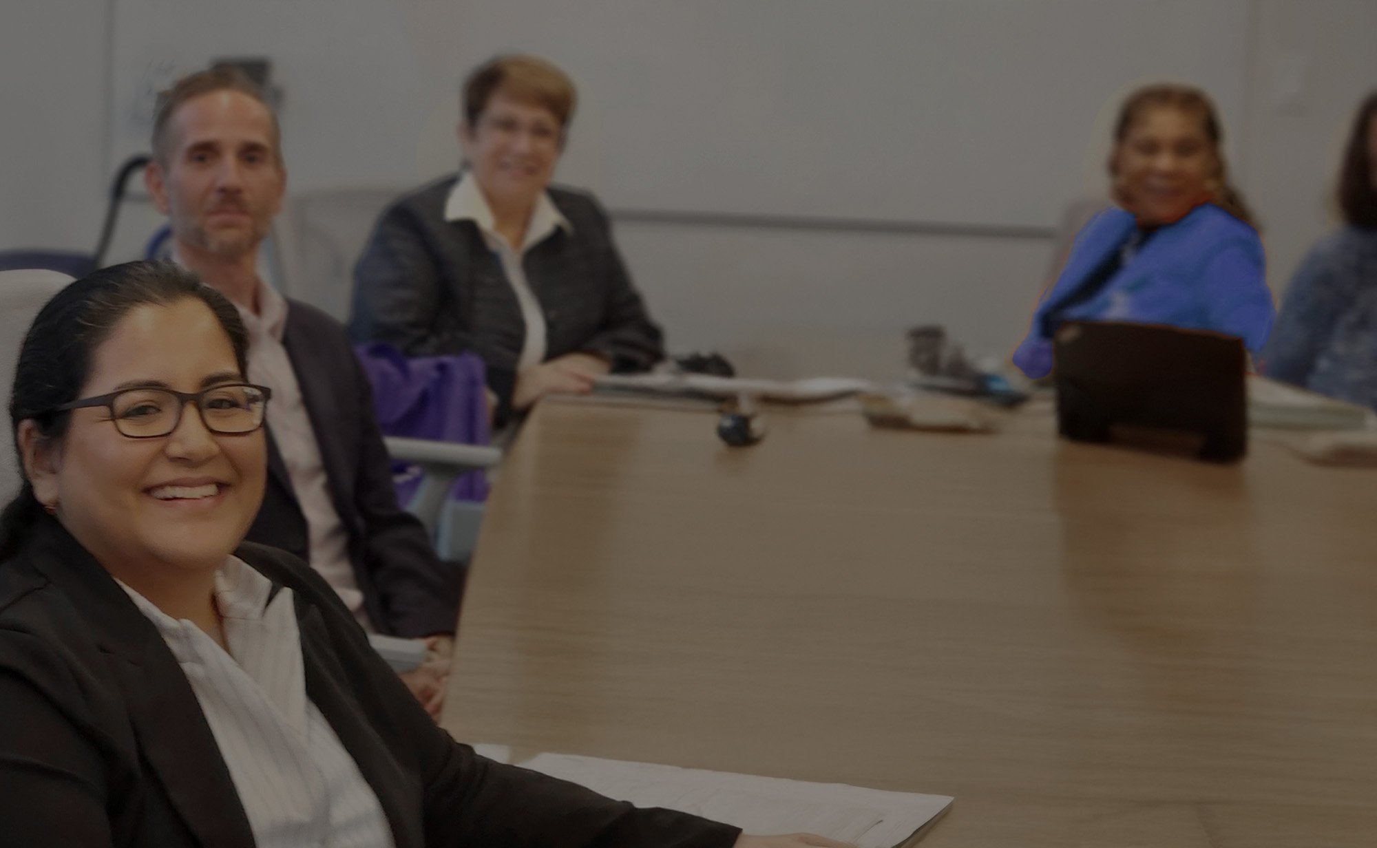 Two women smiling and talking while holding coffee cups in an office setting.