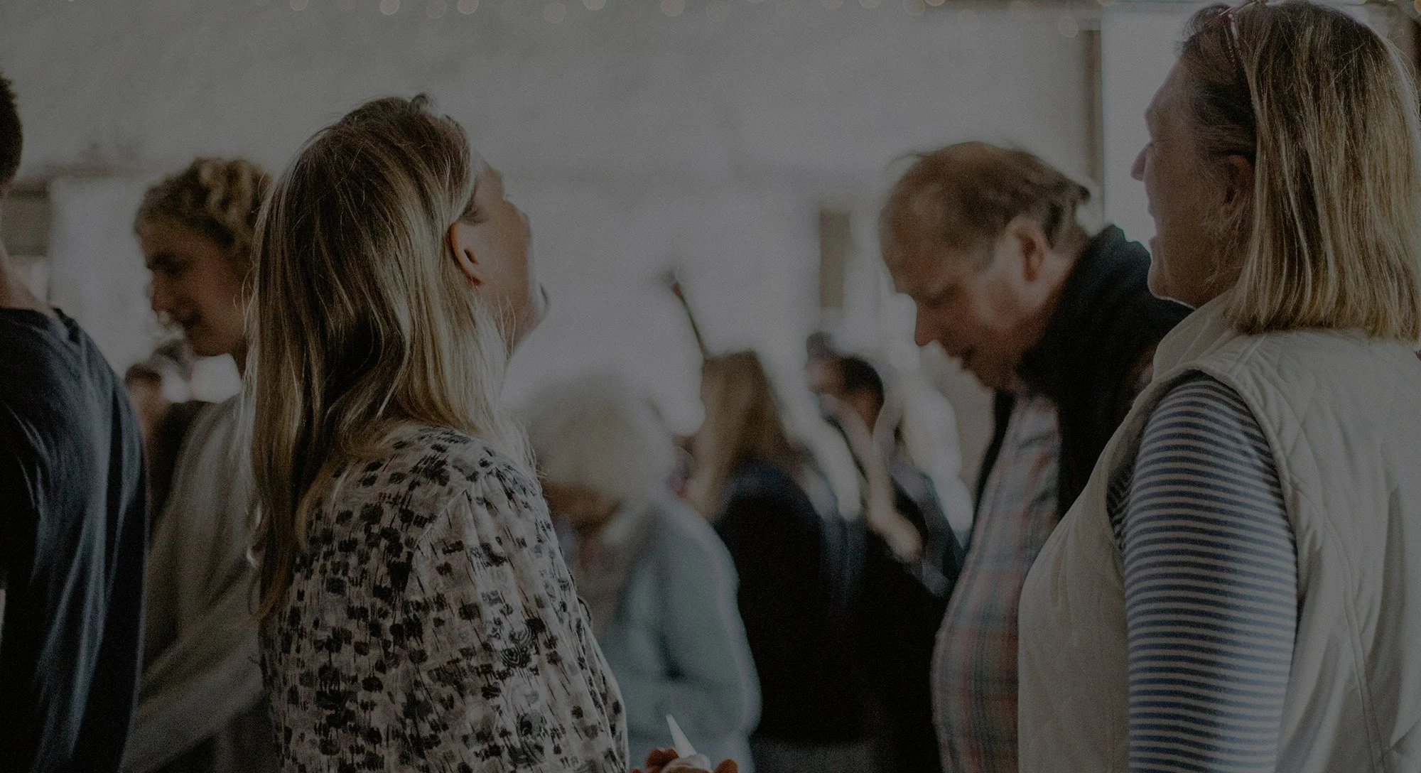 People standing and talking in a social setting, possibly a queue or gathering.