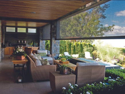 Outdoor patio with wicker furniture, retractable sunshade, and lush garden view