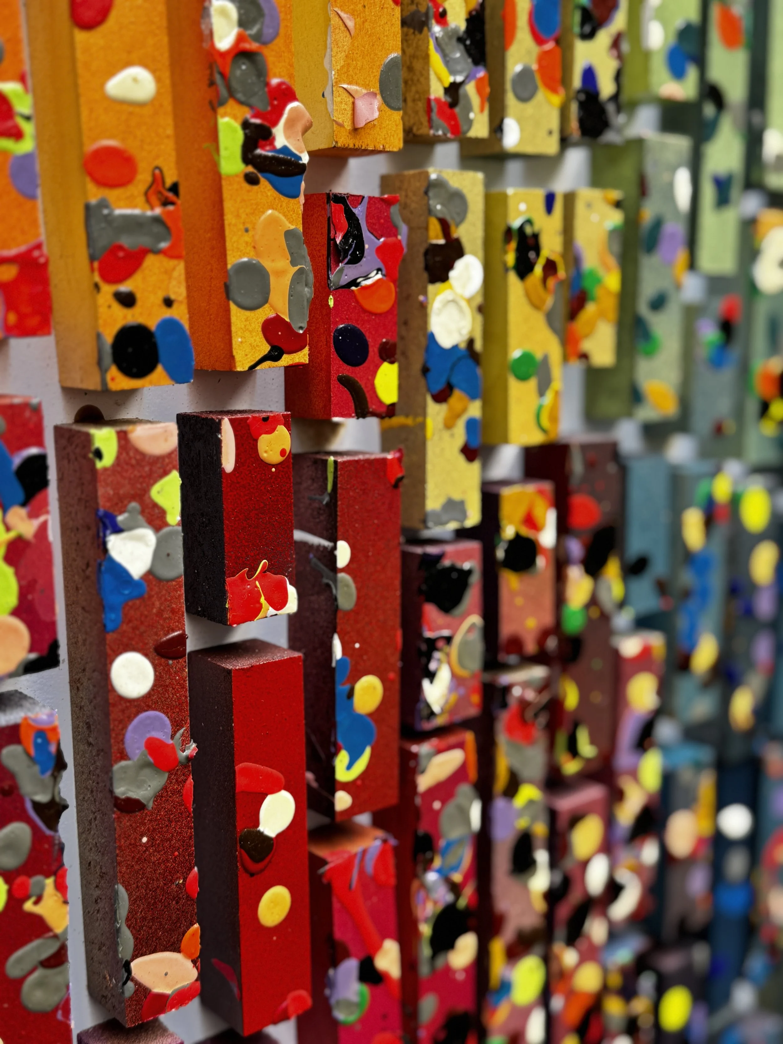 Close-up of colorful painted wooden blocks with multicolored paint splatters and drips.
