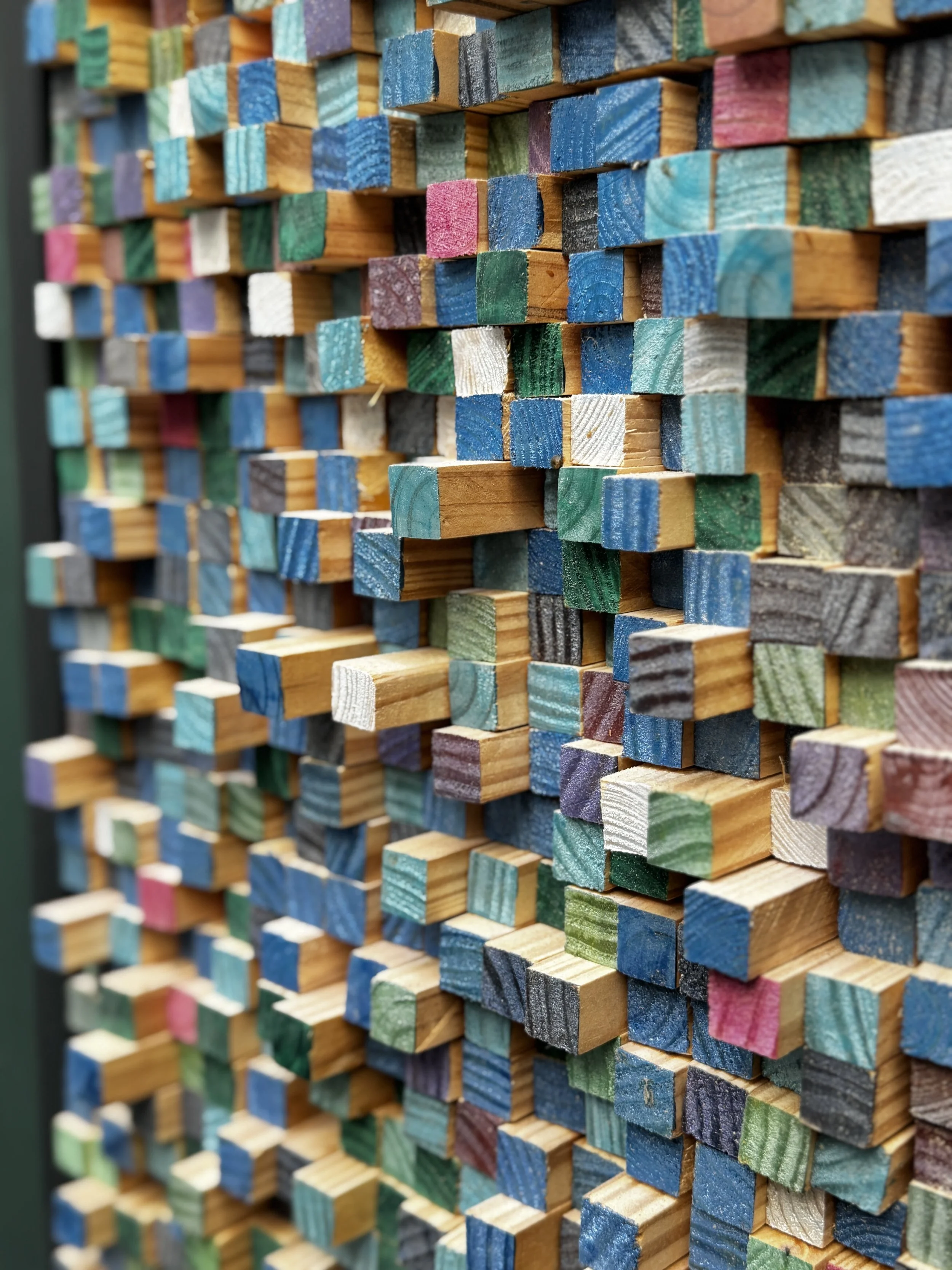 A large stack of multicolored wooden popsicle sticks arranged vertically.