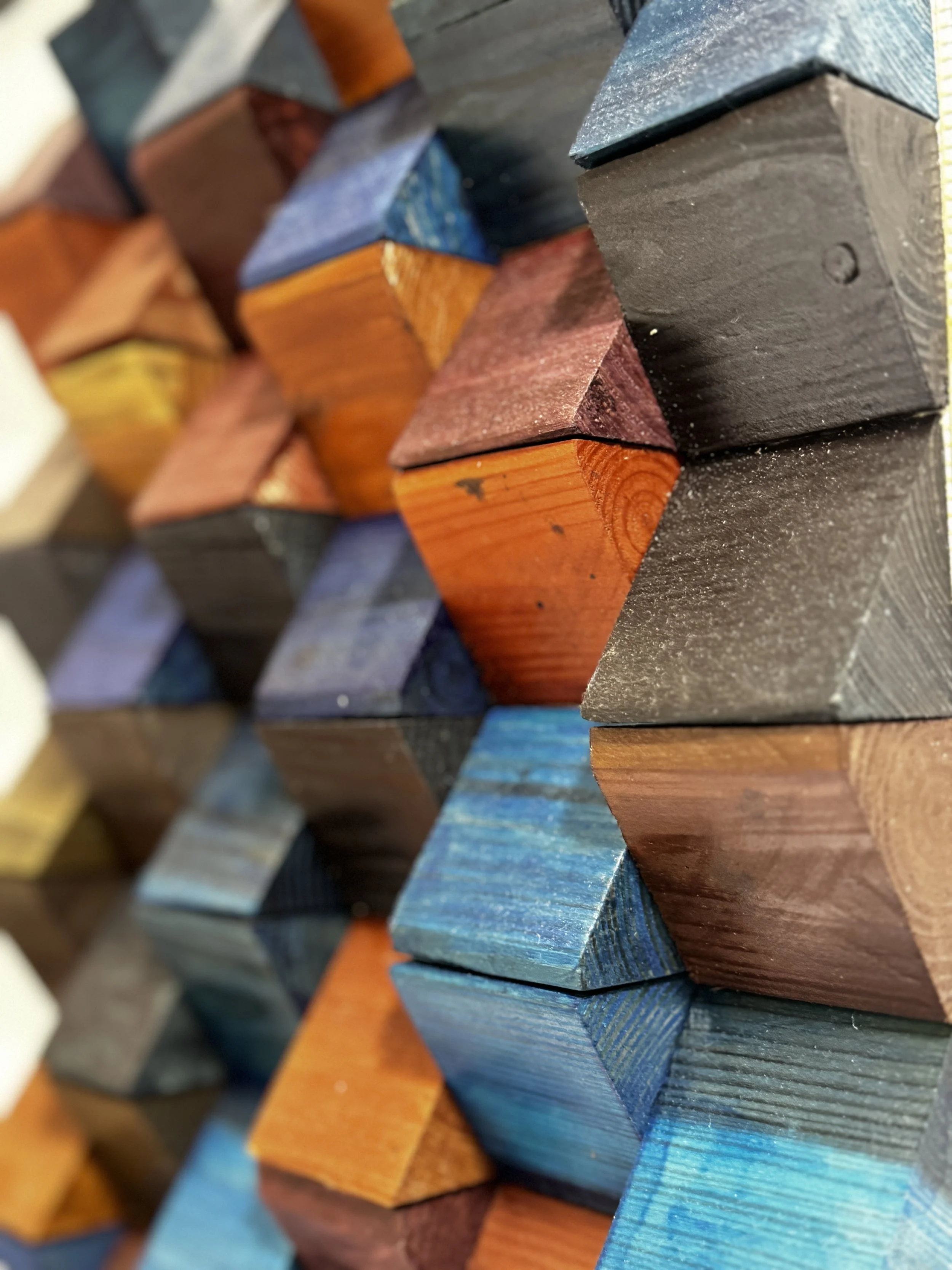 Colorful wooden blocks arranged in a pattern, showing different colors such as blue, red, black, orange, and yellow.