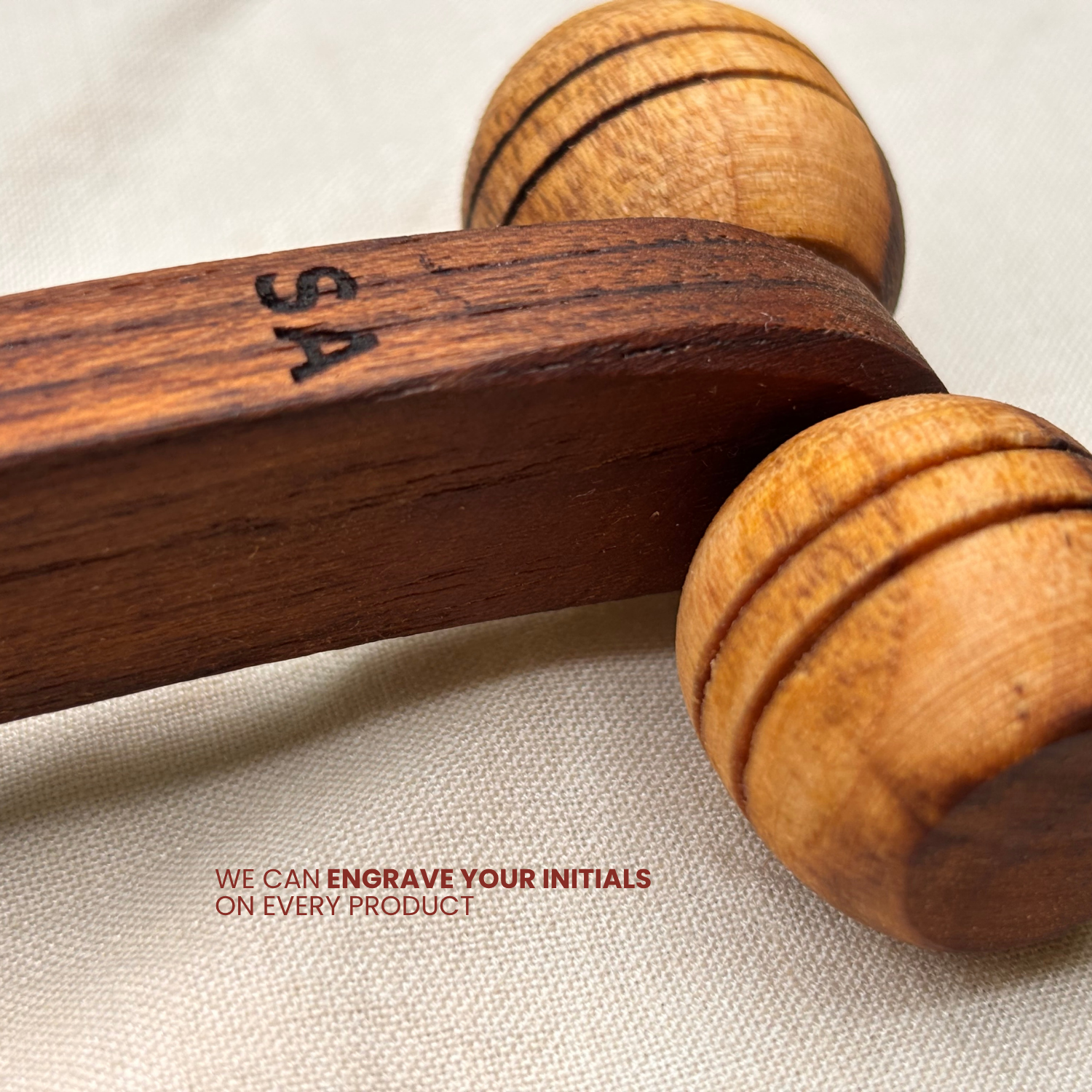 Close-up of a personalised wooden lymphatic face roller with custom initials engraved into the wooden handle.