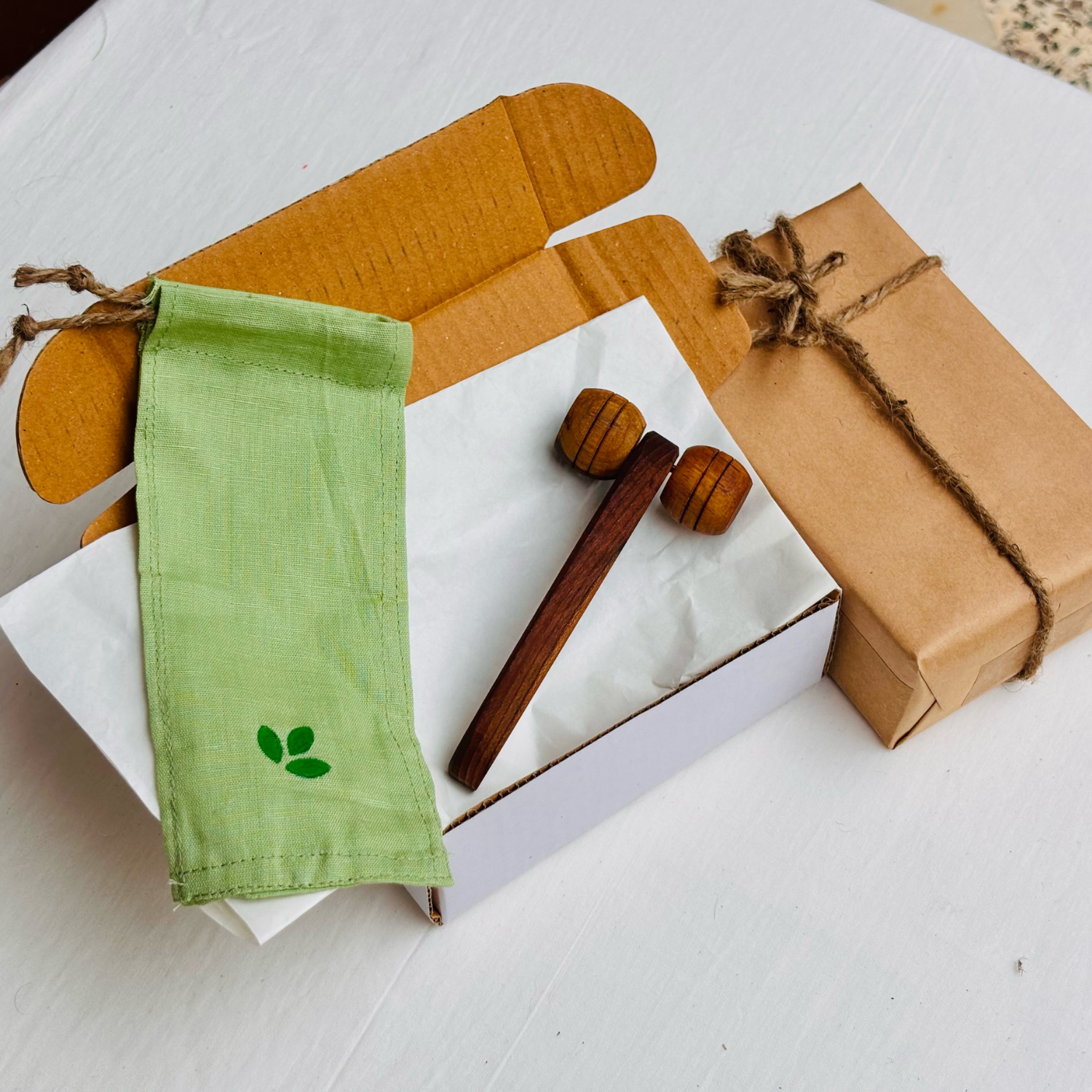 Wooden lymphatic face roller presented with recyclable cardboard packaging and a reusable cotton drawstring pouch.