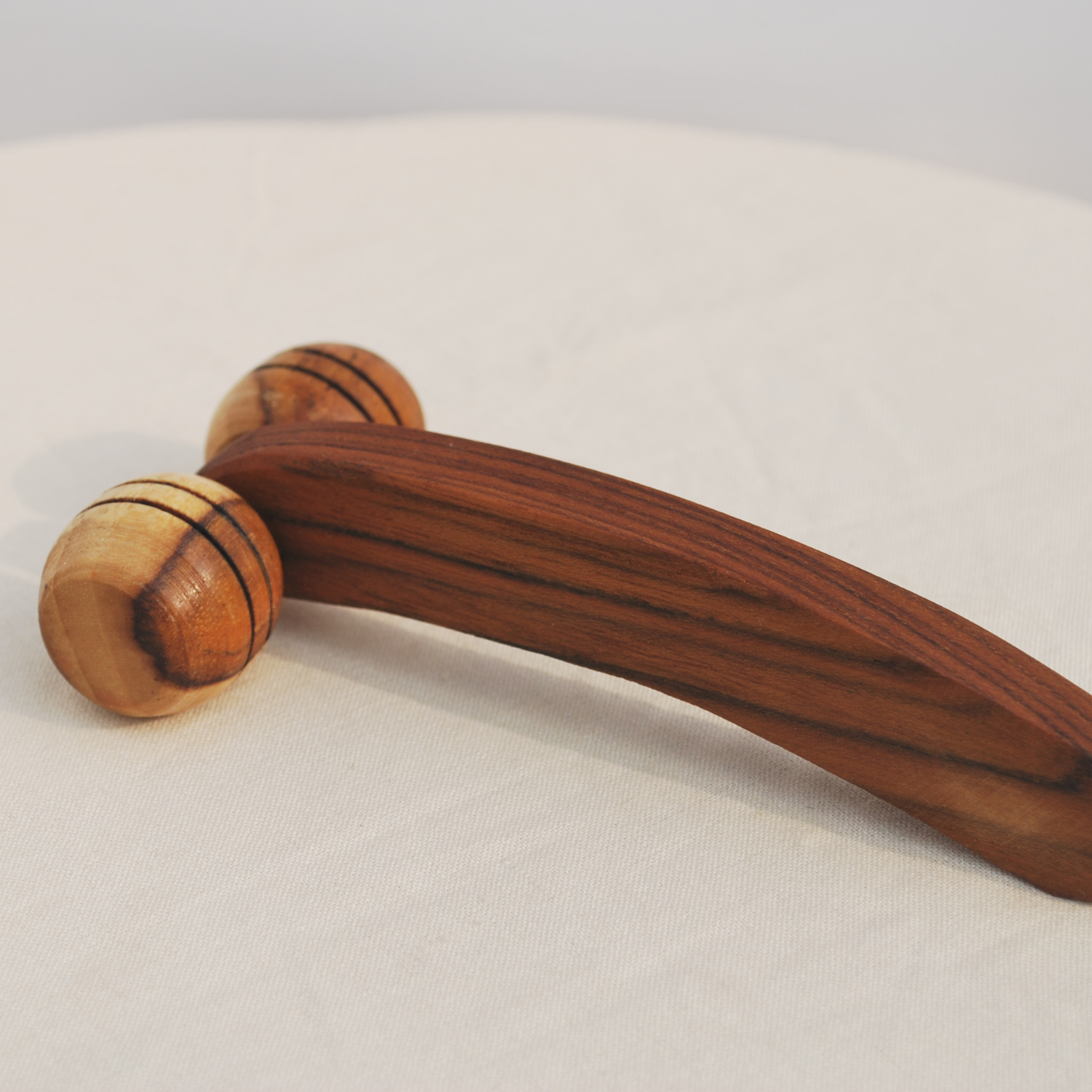 Side view of a handmade wooden lymphatic face roller showing the curved handle, dual rollers and natural wood grain.