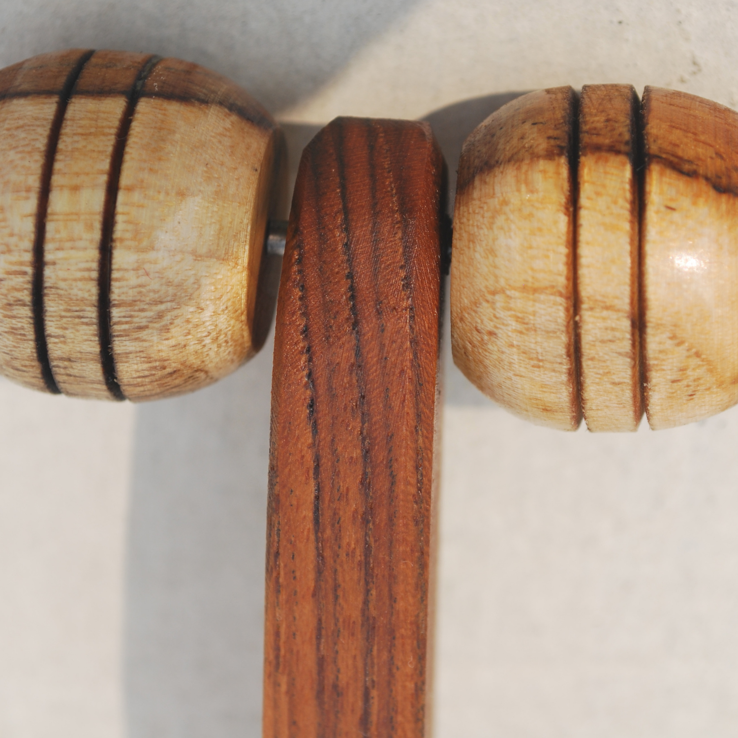Close-up of the dual rounded wooden rollers, natural wood grain and curved handle of a lymphatic face roller.