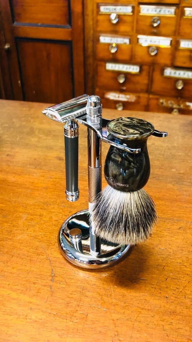 Shaving set with razor, brush, and stand on wooden surface.