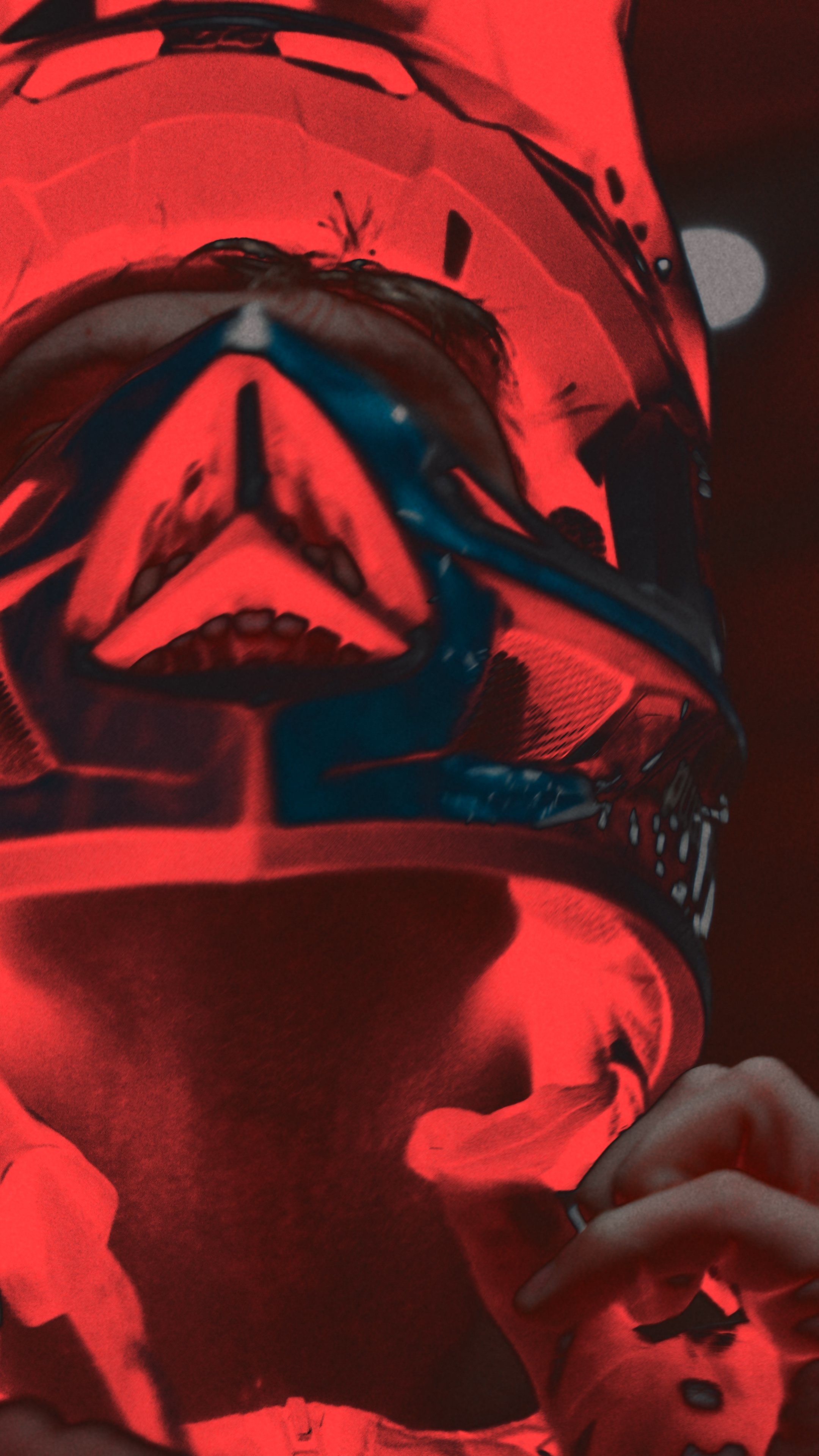 A person holding his bycicle helmet. The image is taken from an upward angle and has a red filter effect.