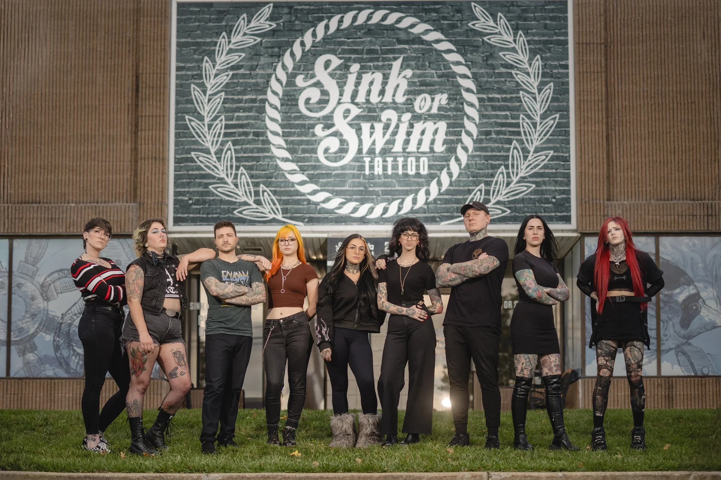 The professional tattoo artists and body piercers crew standing in front of Sink or Swim Tattoo studio storefront on Niagara Falls Boulevard near Buffalo NY