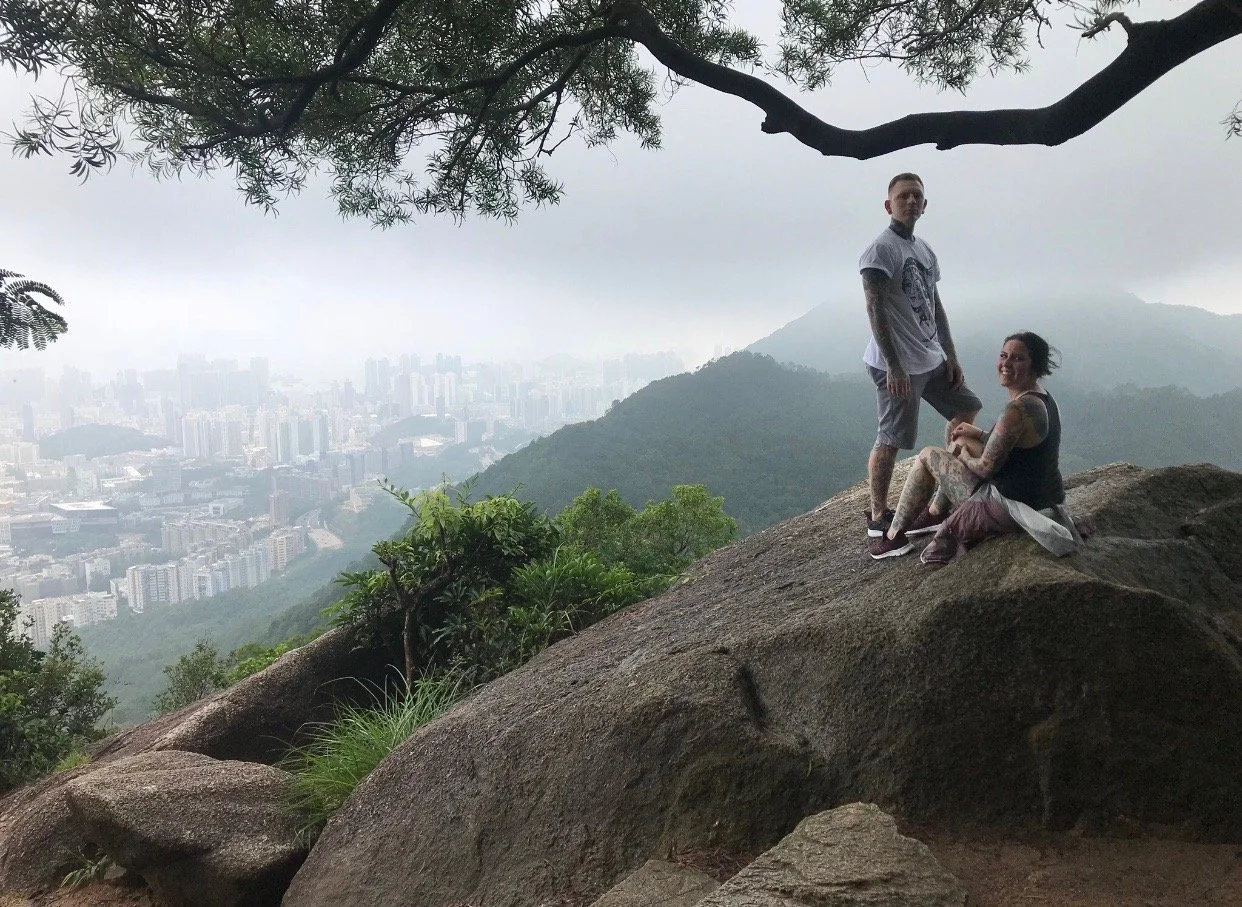 shannon and Keith posing outside of Hong Kong with the city in the background
