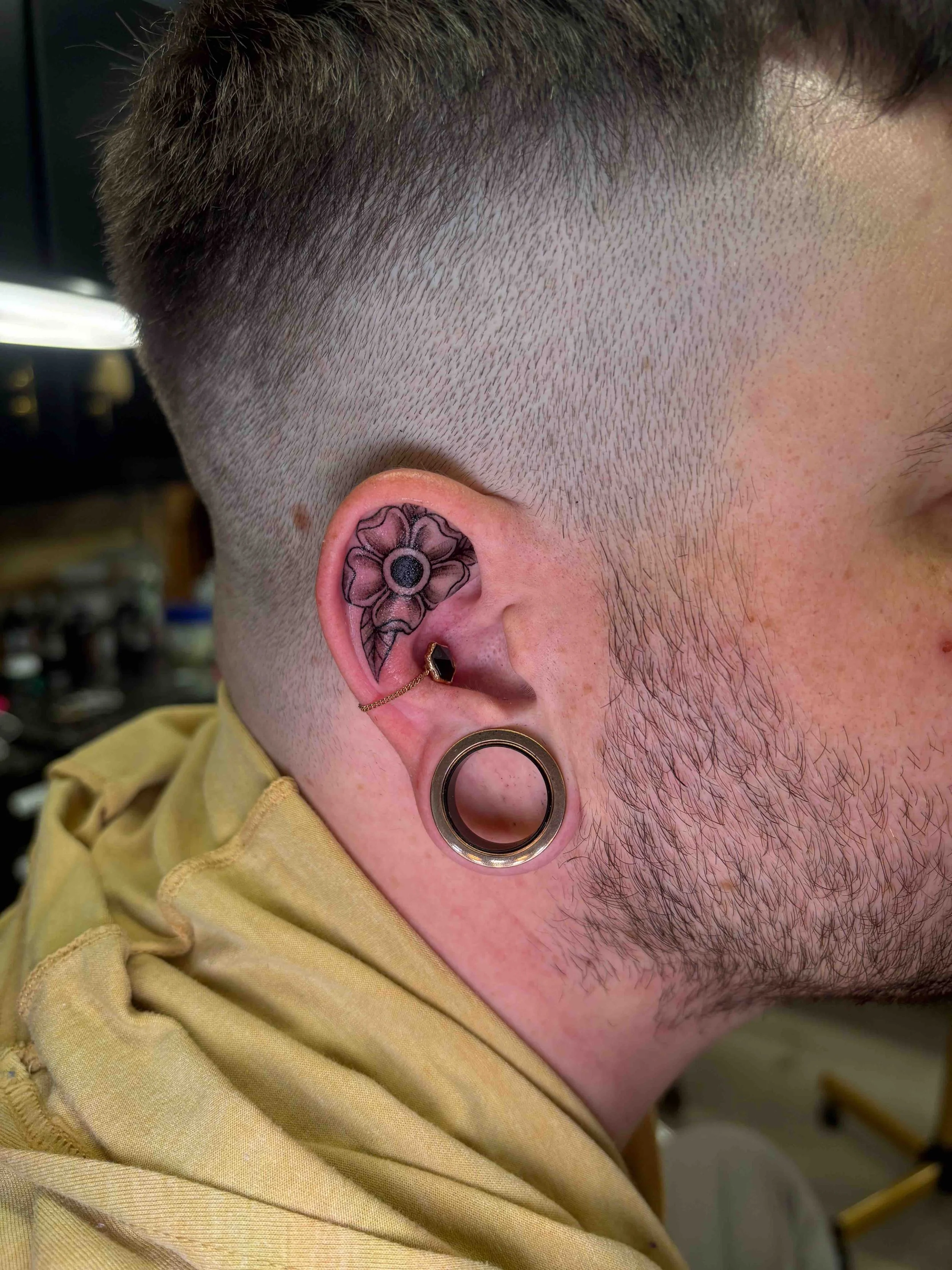 black and grey style flower on inner ear, portfolio work by Brooke Canzoneri at sink or swim tattoo and piercing in Niagara Falls, ny