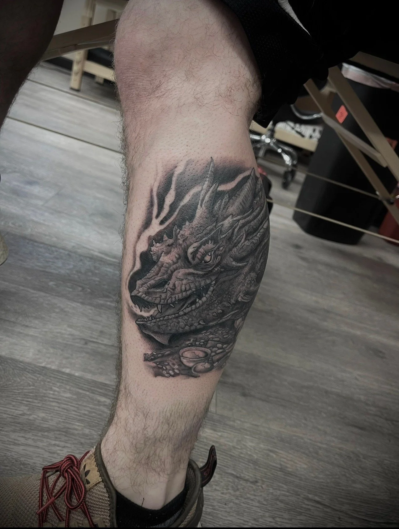 black and grey dragon, smaug on calf , portfolio work by Brooke Canzoneri at sink or swim tattoo and piercing in Niagara Falls, ny