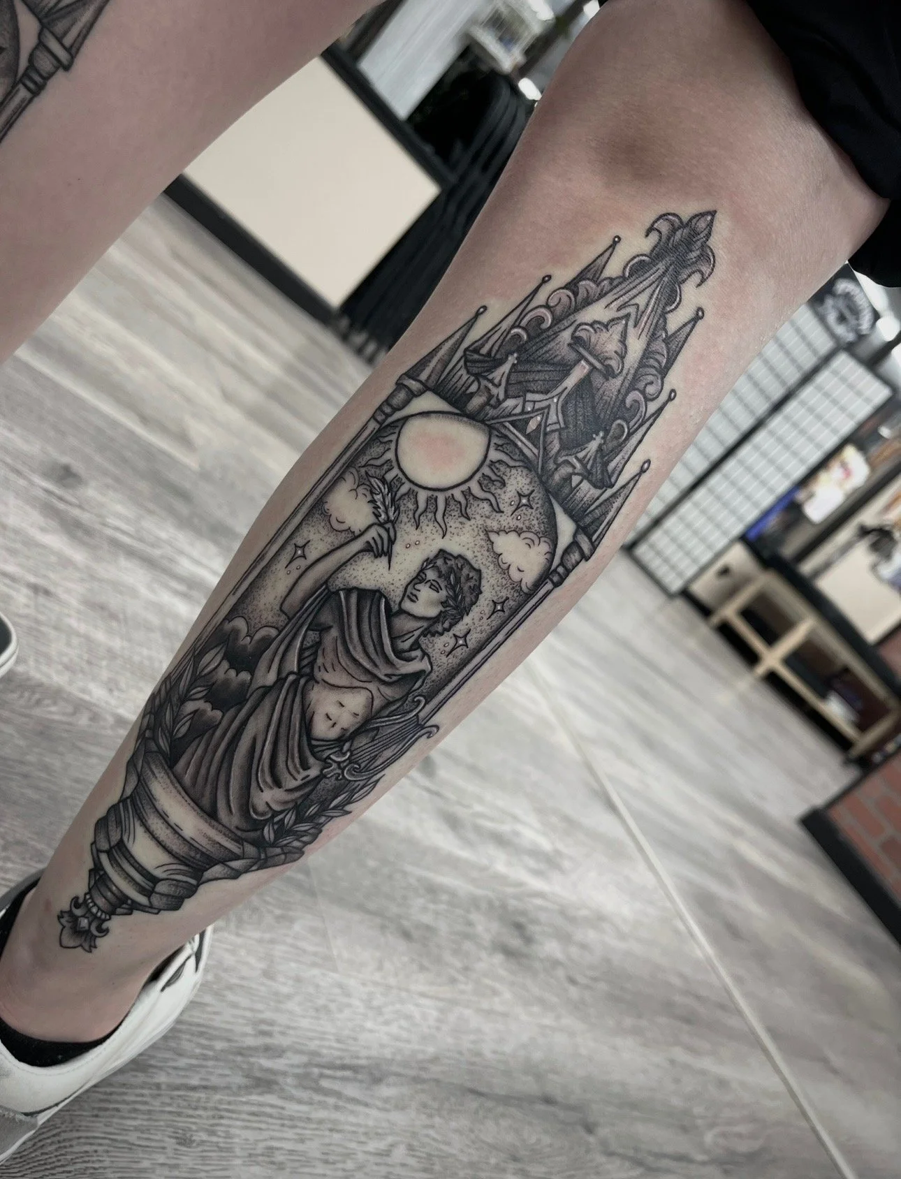 black and grey Apollo tattoo on calf , portfolio work by Brooke Canzoneri at sink or swim tattoo and piercing in Niagara Falls, ny