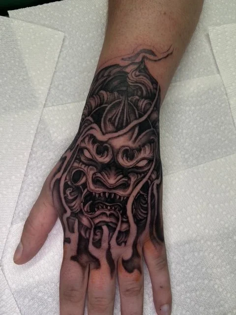 dark art black and grey Japanese fu dog hand tattoo , portfolio work by Jordy Levea at sink or swim tattoo and piercing in Niagara Falls, ny