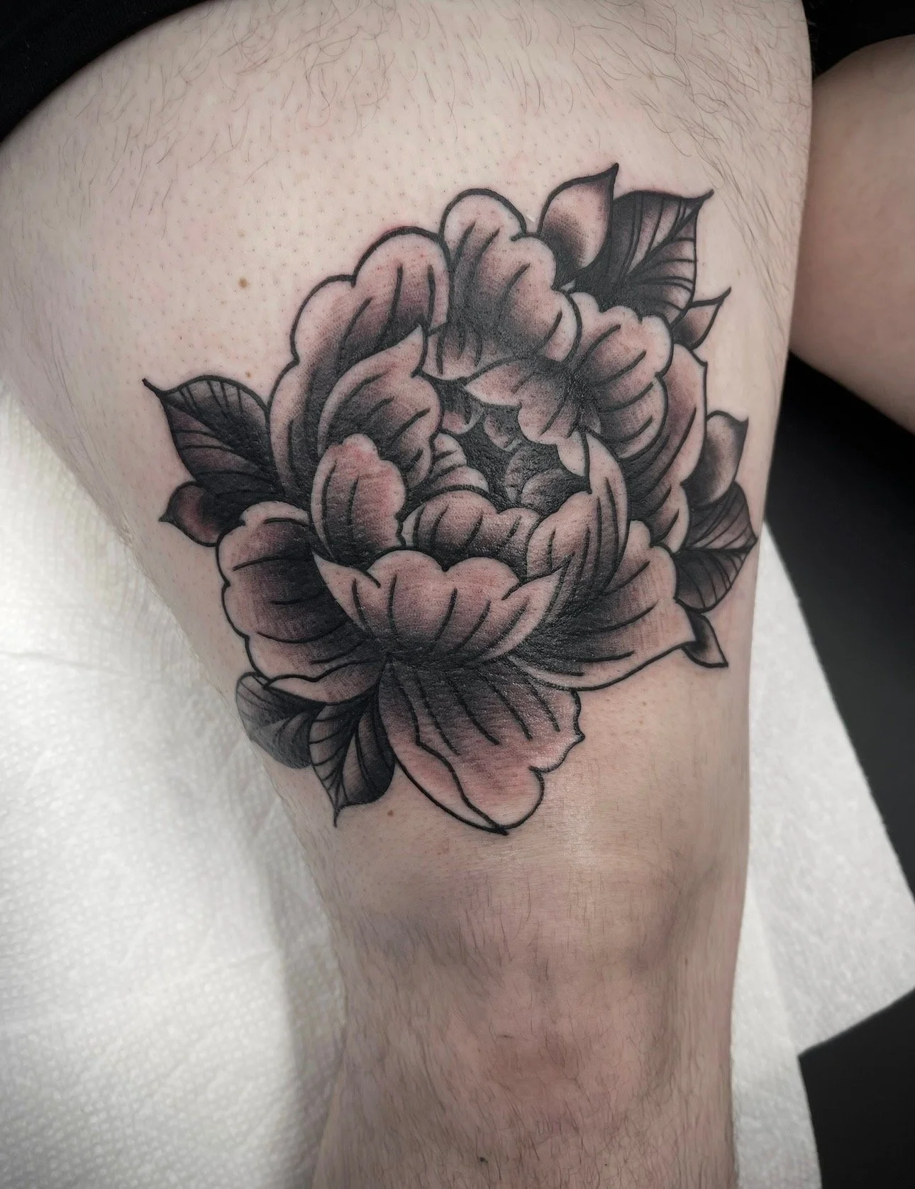 black and grey peony tattoo above knee , portfolio work by Brooke Canzoneri at sink or swim tattoo and piercing in Niagara Falls, ny