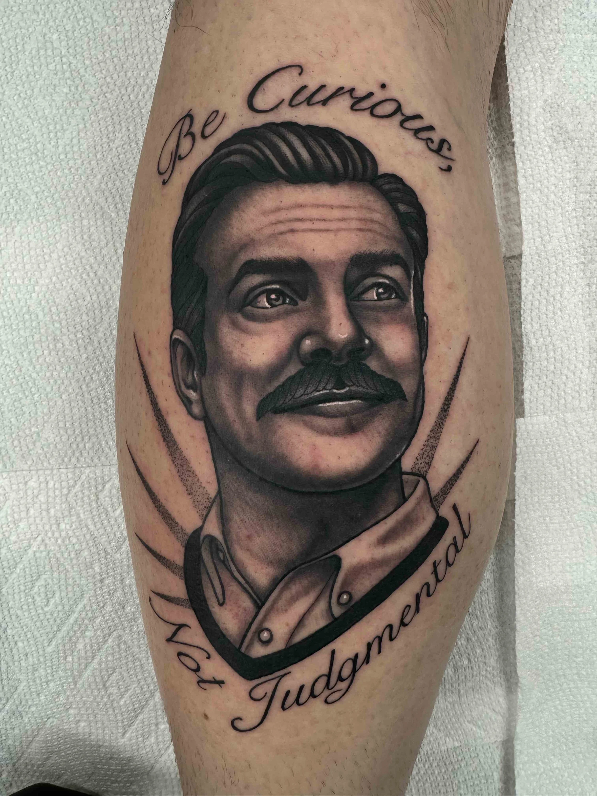 Mixed style of Realism and Neo traditional Ted Lasso portrait tattoo in black and grey, portfolio work by Keith Kuzara at Sink or Swim Tattoo and Piercing in Niagara Falls NY