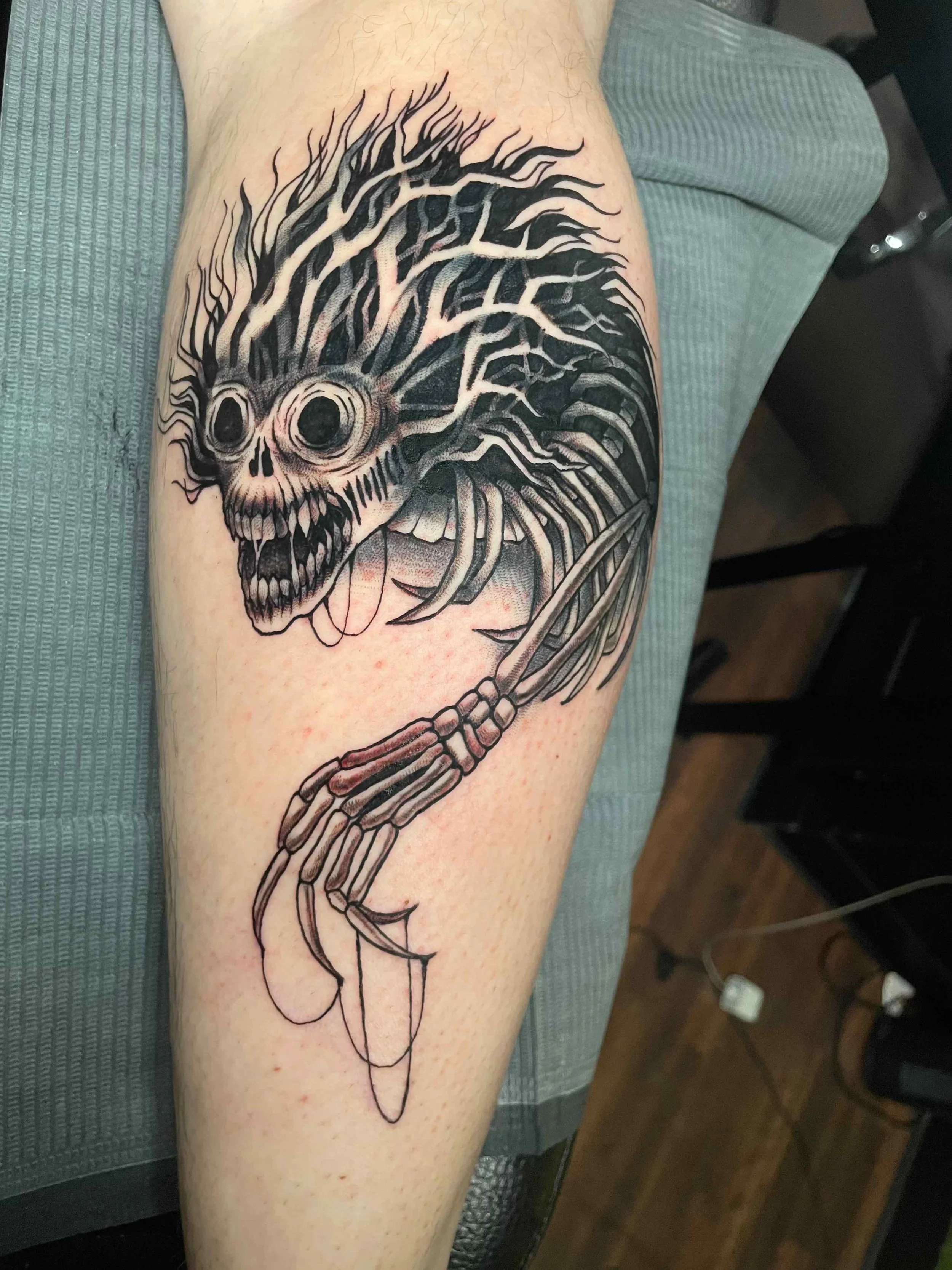 Black and grey illustrative skull and fish tattoo, portfolio work by Emily Quartley at Sink or Swim Tattoo and Piercing in Niagara Falls, NY