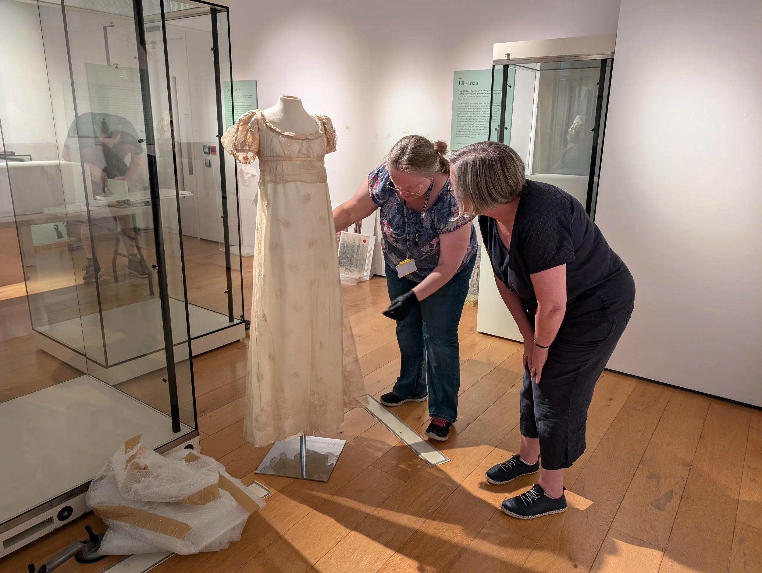 Kathleen and conservator Ruth examine a lace dress during exhibition installation.