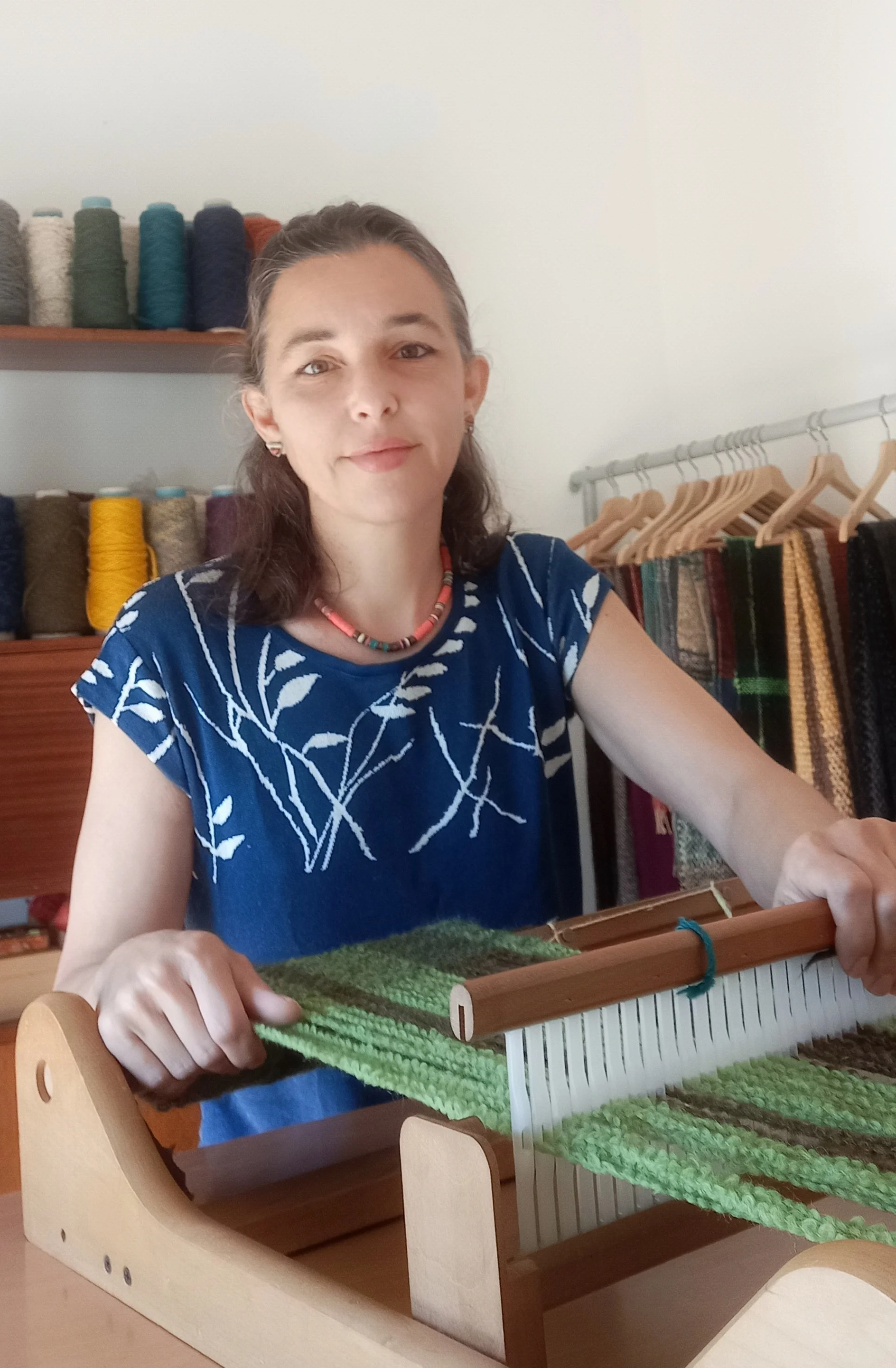 Young man sitting on a beige cushioned bench against a cream wall, wearing a gray polo shirt and cream pants, with shadow cast on the wall.