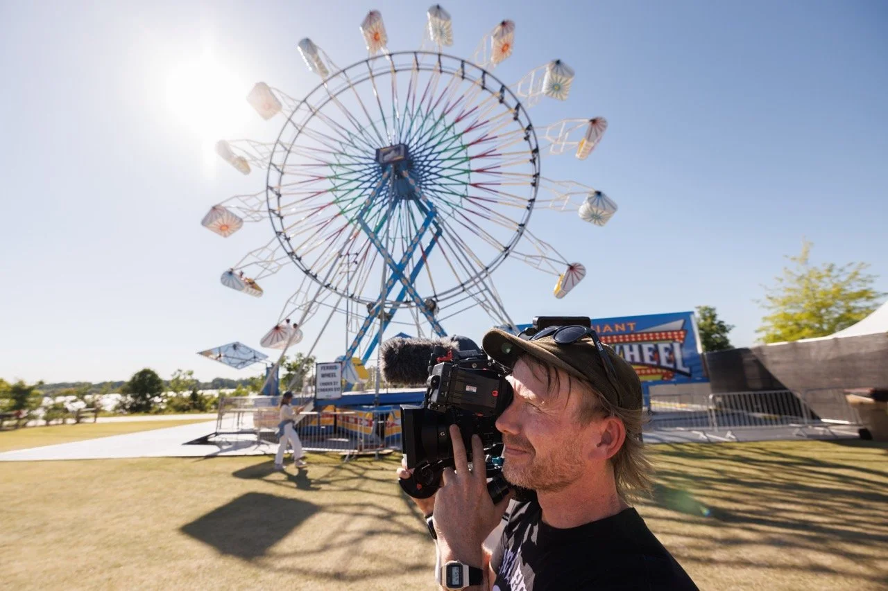Cinematographer Matt Fremstad films near the ferris wheel at RiverBeat Music Fest 2026 for Agency. Tom Lee Park, Memphis.