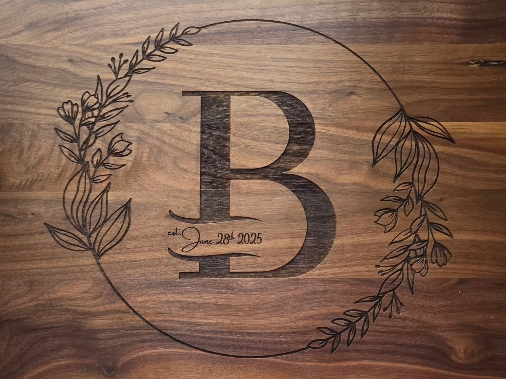 Walnut cutting board engraved with a large monogram B inside a floral wreath, with an established date in script