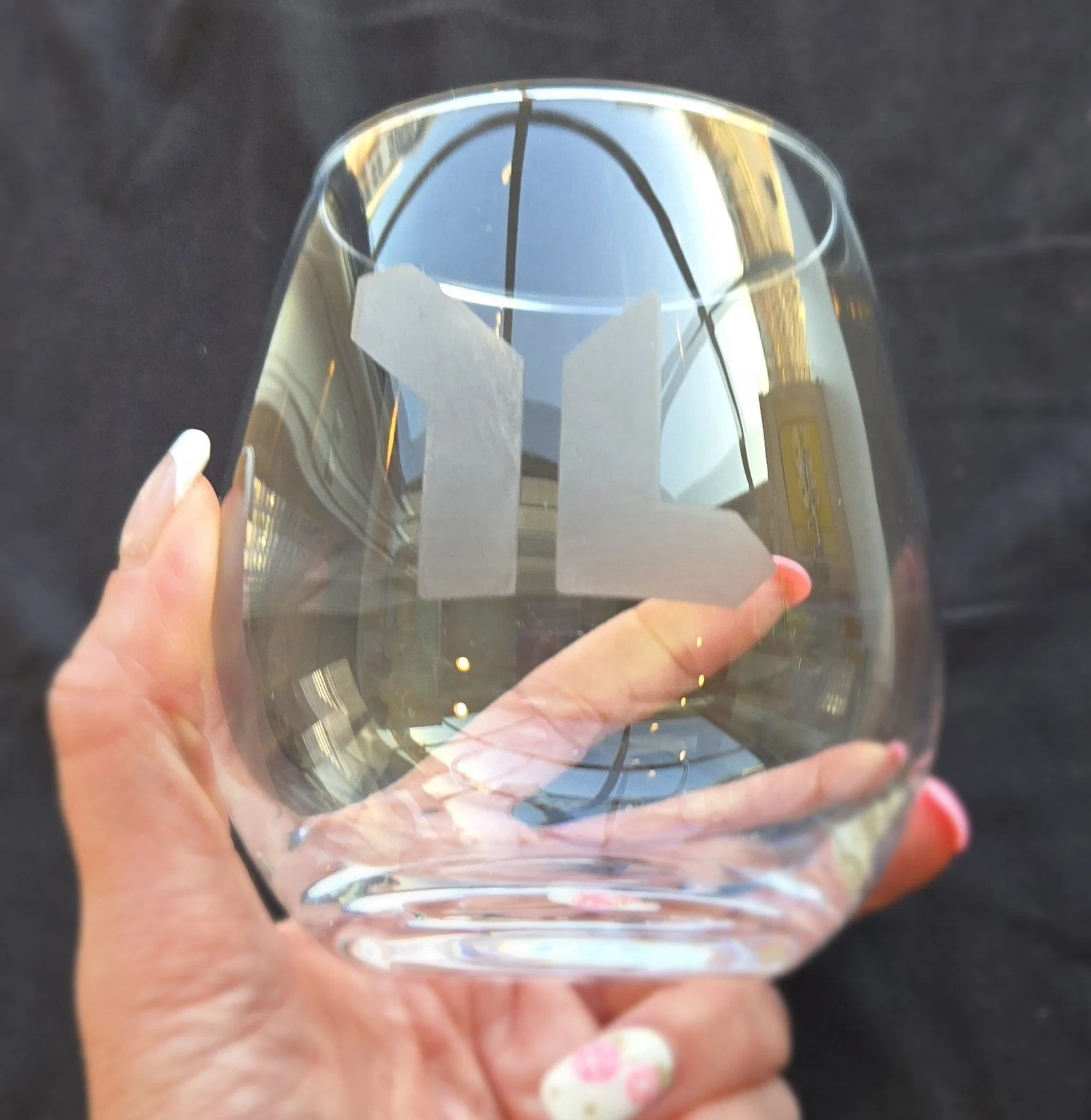 Hand holding a stemless wine glass etched with the Young Life logo