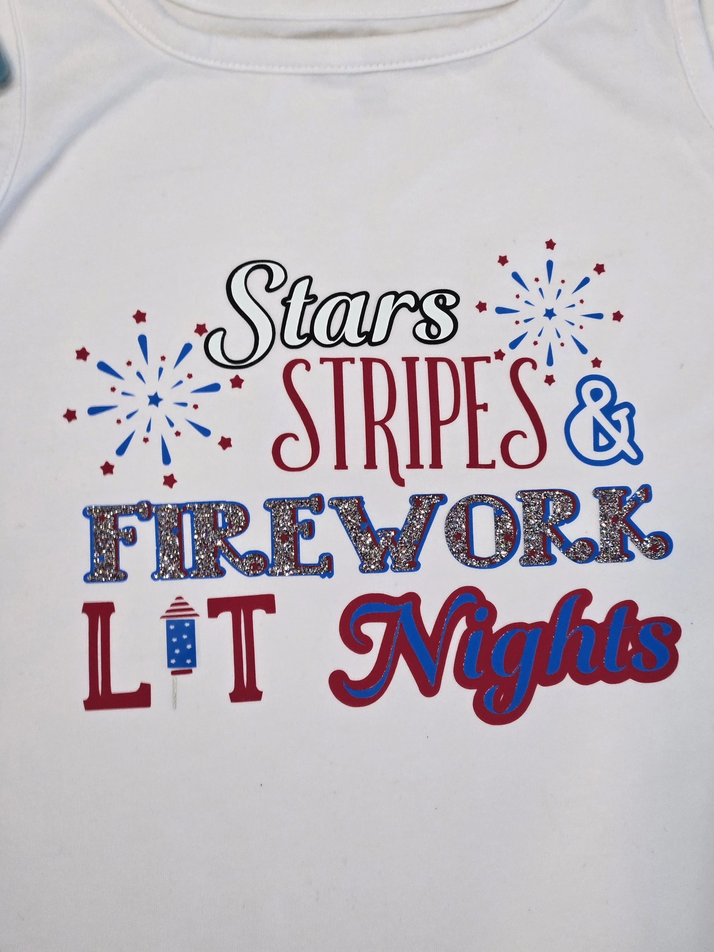 White shirt with a red, white, and blue Stars, Stripes and Firework Lit Nights design with fireworks