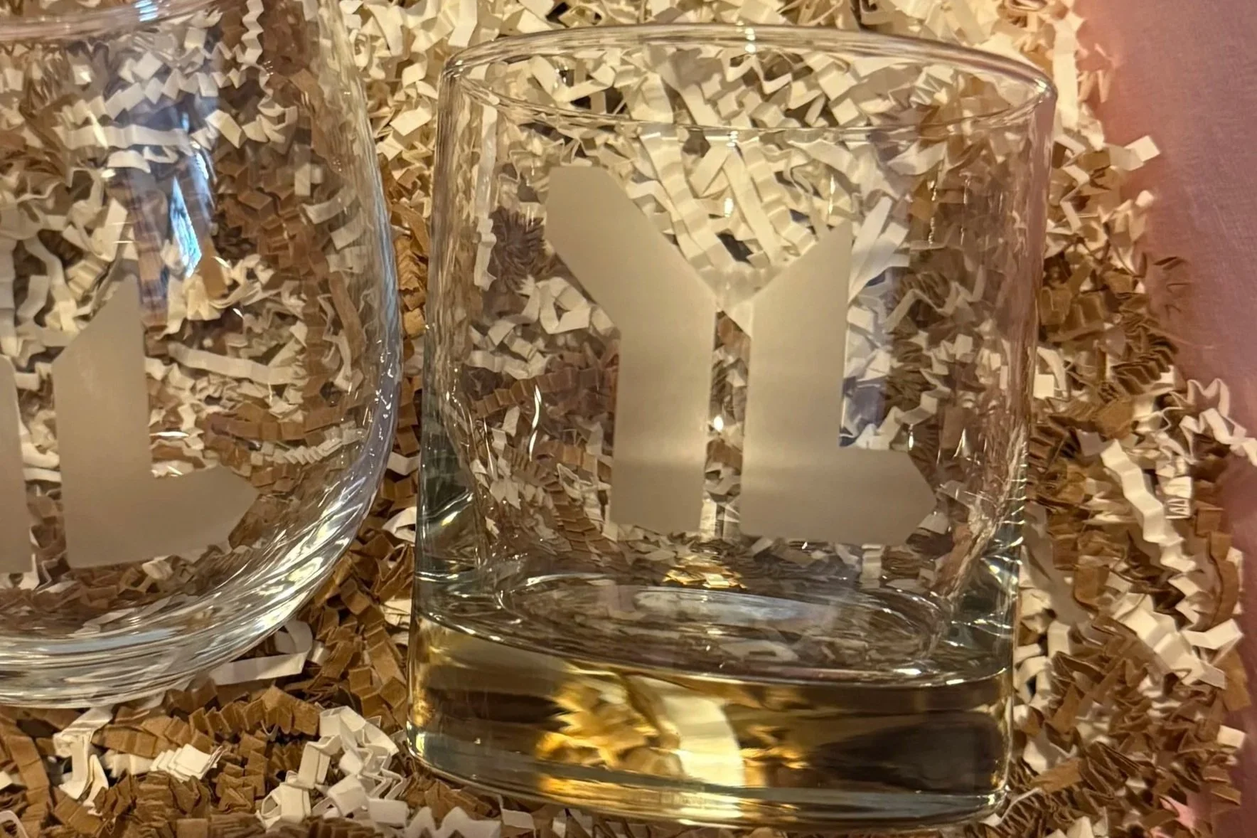 Rocks glass and stemless wine glass etched with the Young Life logo, set in crinkle paper