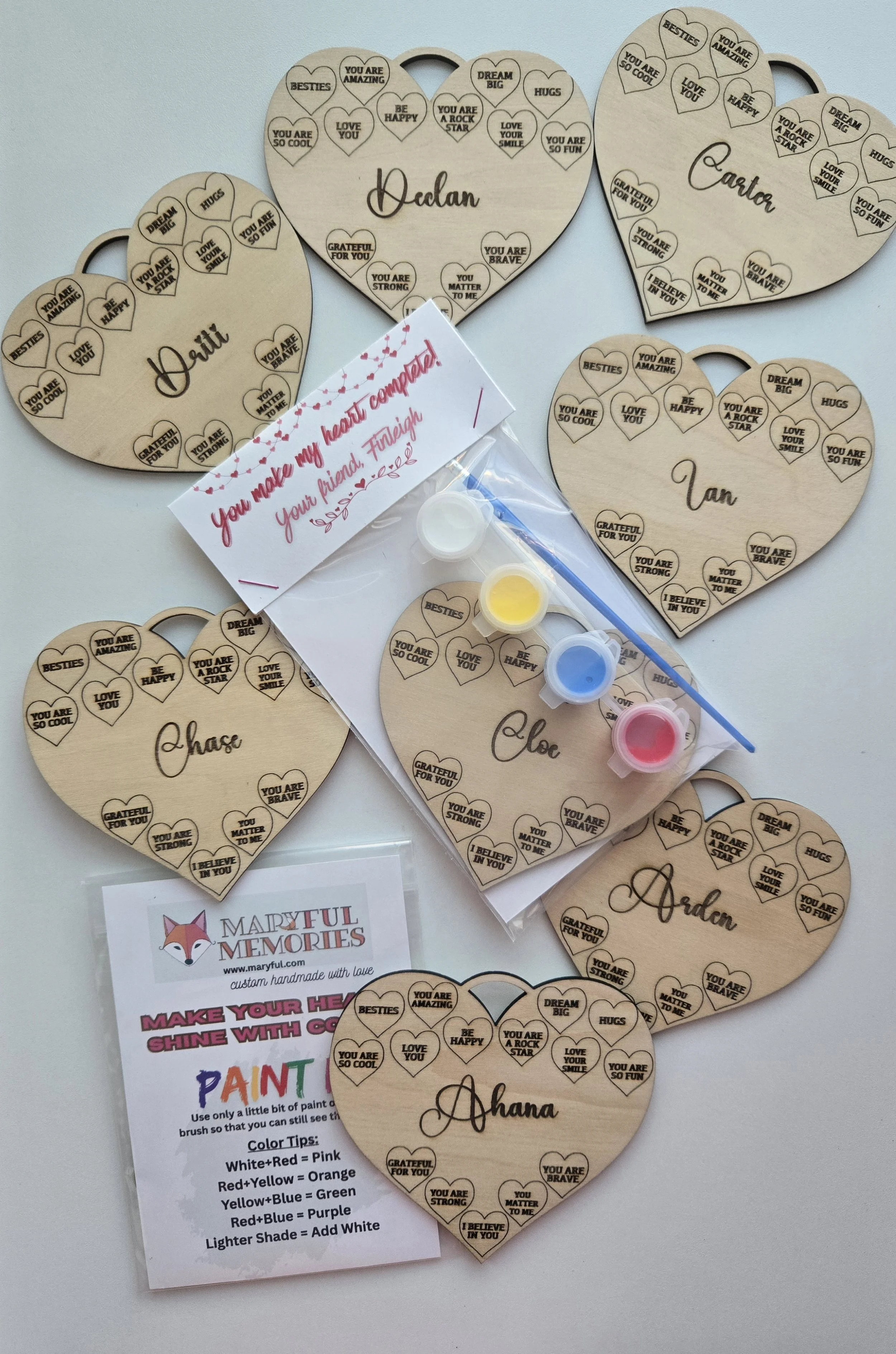 Wooden conversation heart plaques, each engraved with a child's name, with a paint set, brush, and instruction card