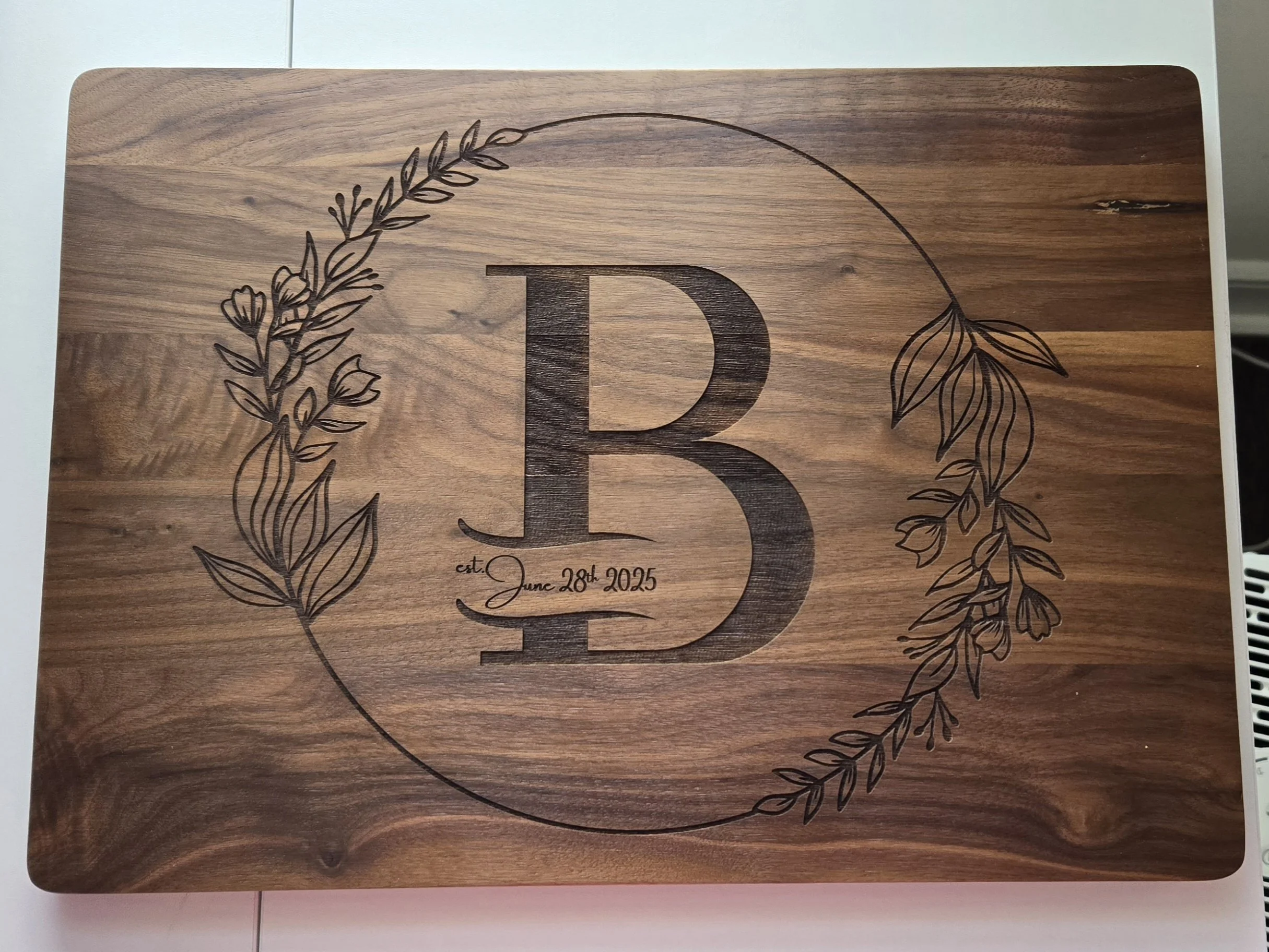 Walnut cutting board with an engraved B with est June 28th 2025 in the decorative circle