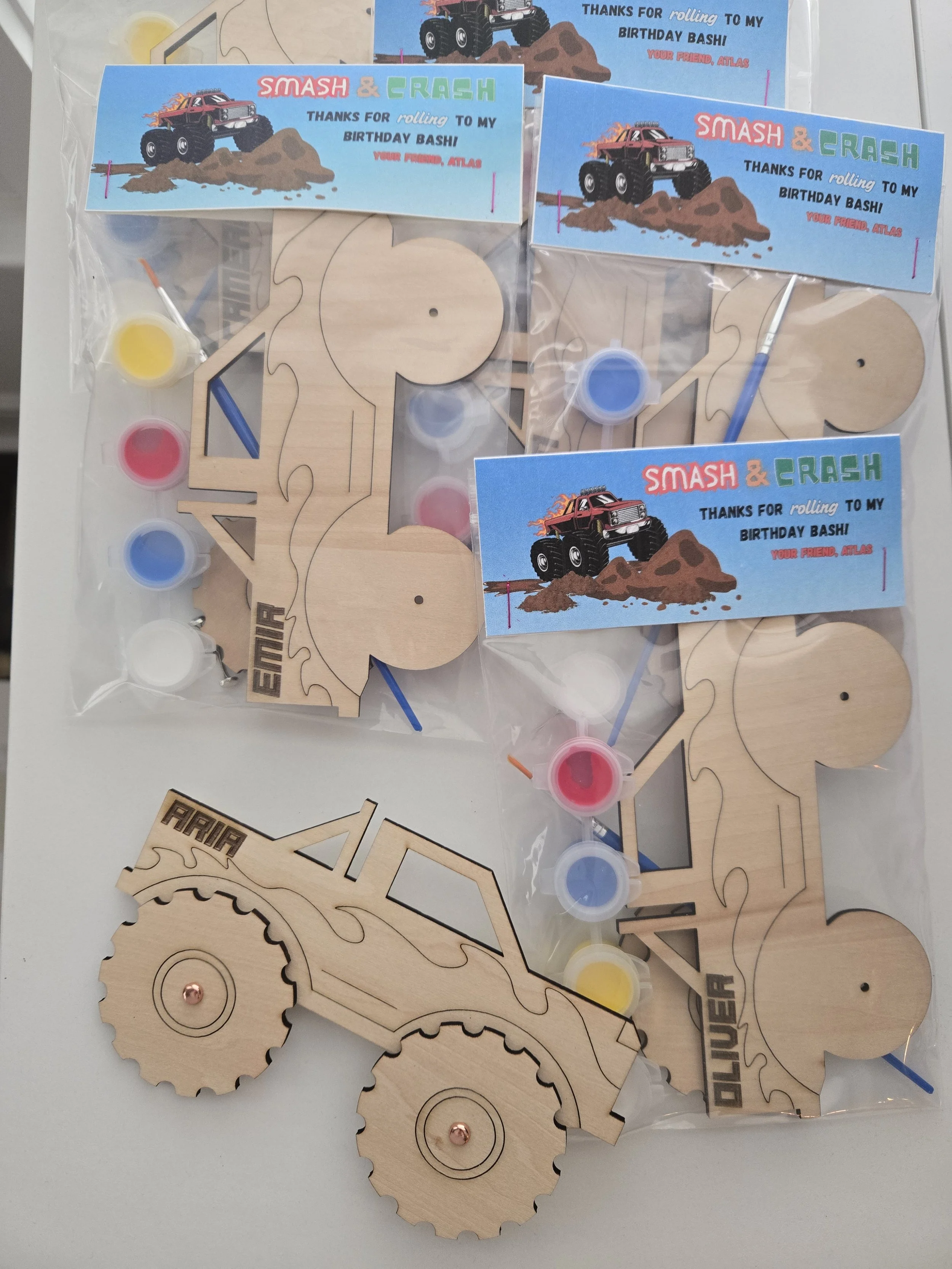 Monster truck paint kits with wooden trucks personalized with names, paint pots, brushes, and Smash and Crash birthday thank-you tags
