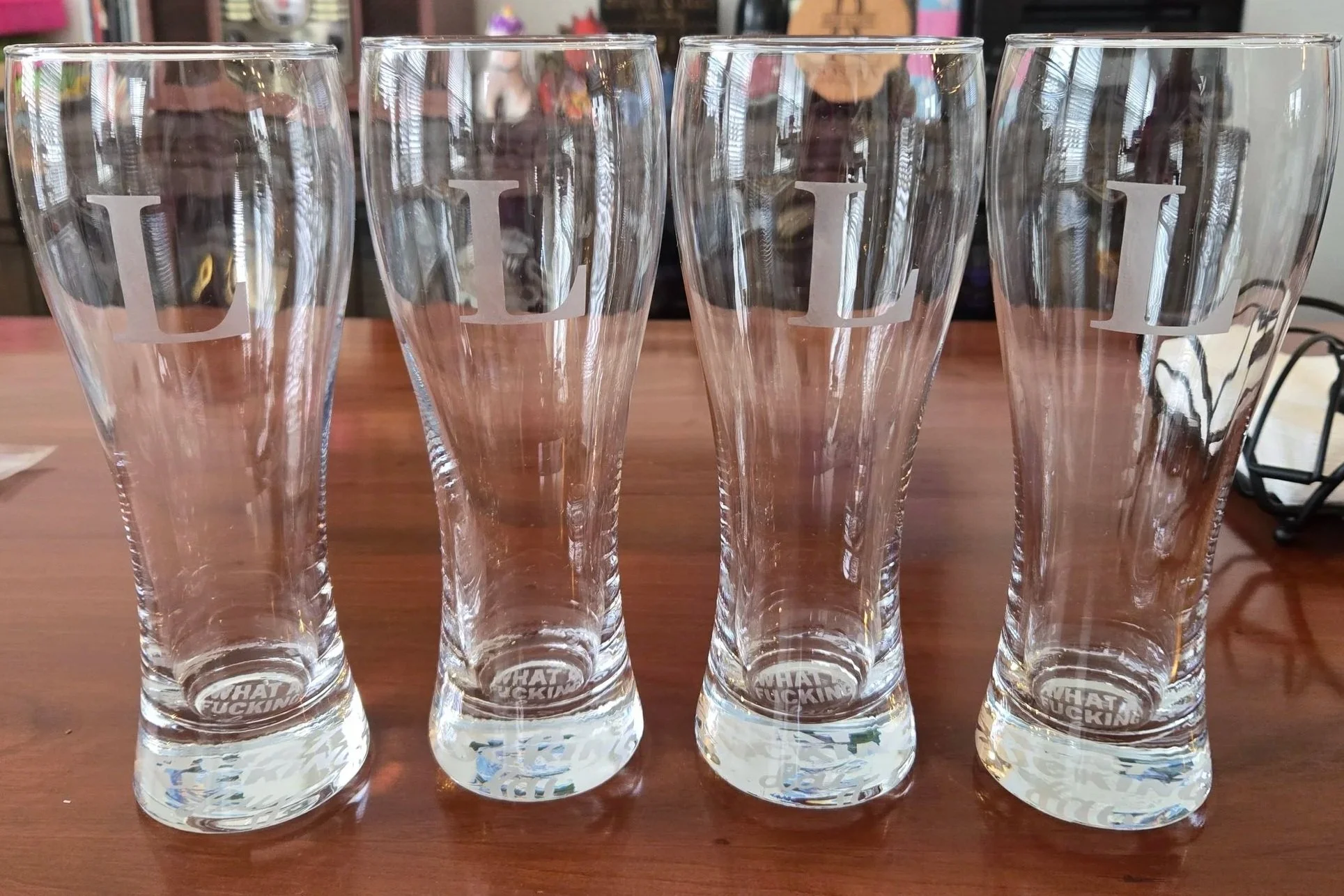 Set of four pilsner beer glasses, each etched with a matching initial