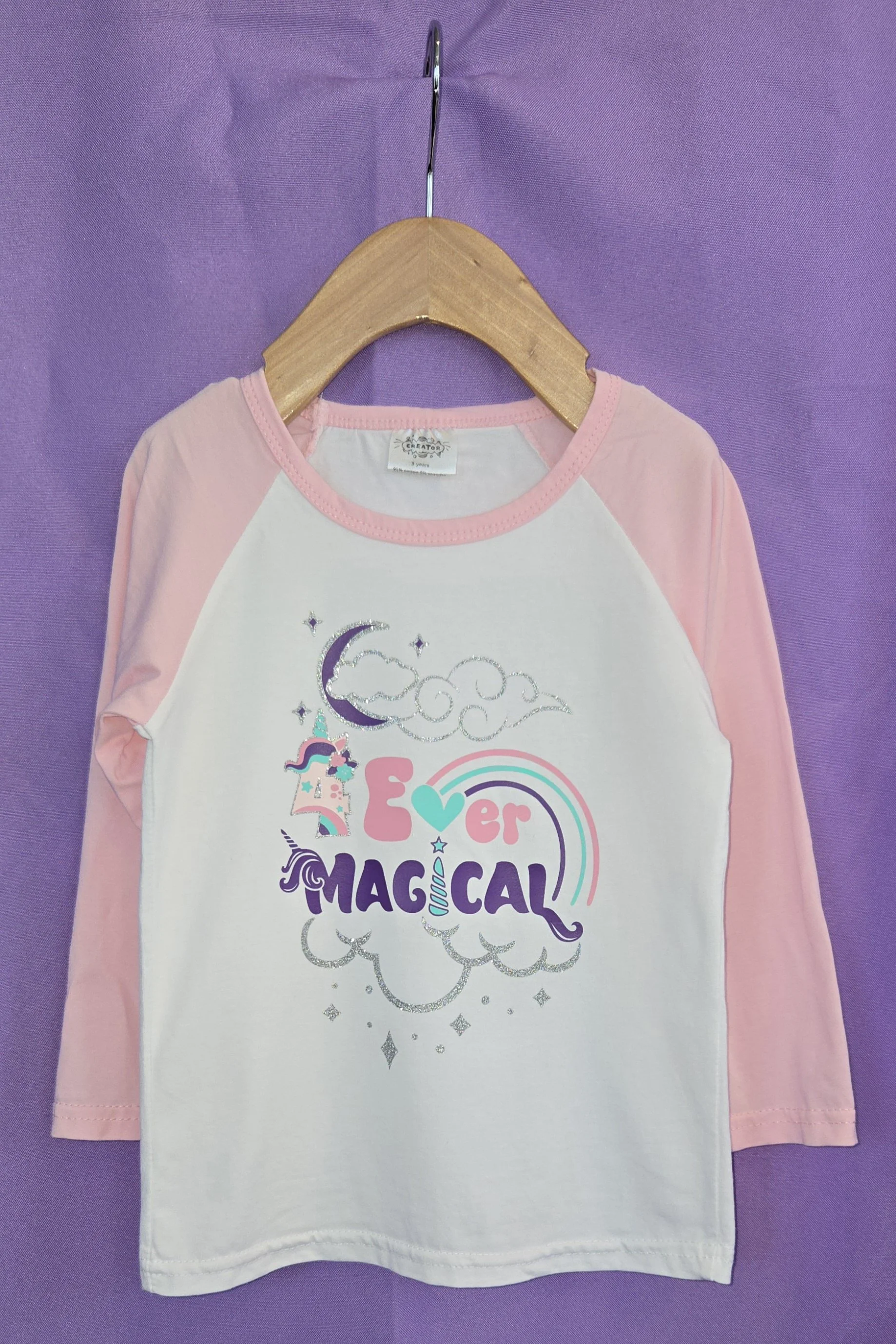 Pink and white raglan birthday shirt with a unicorn, rainbow, crescent moon, and the word Magical