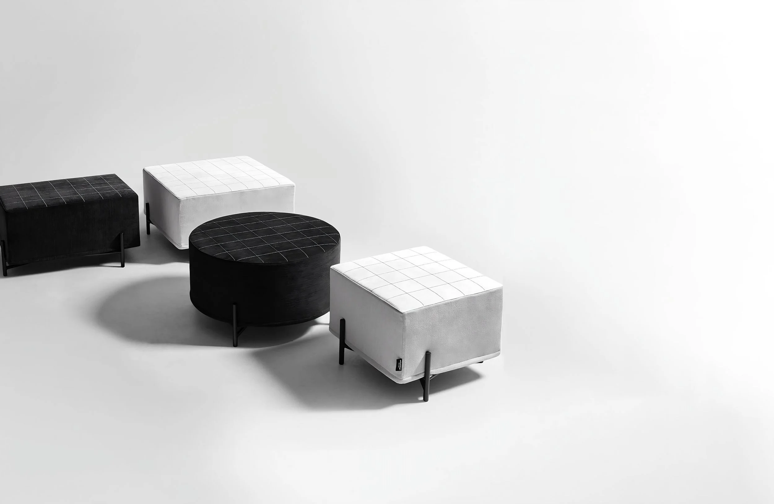 Complessi di arredi di diverse forme e colori posizionati su una superficie bianca, con sfondo bianco e ombre evidenti.