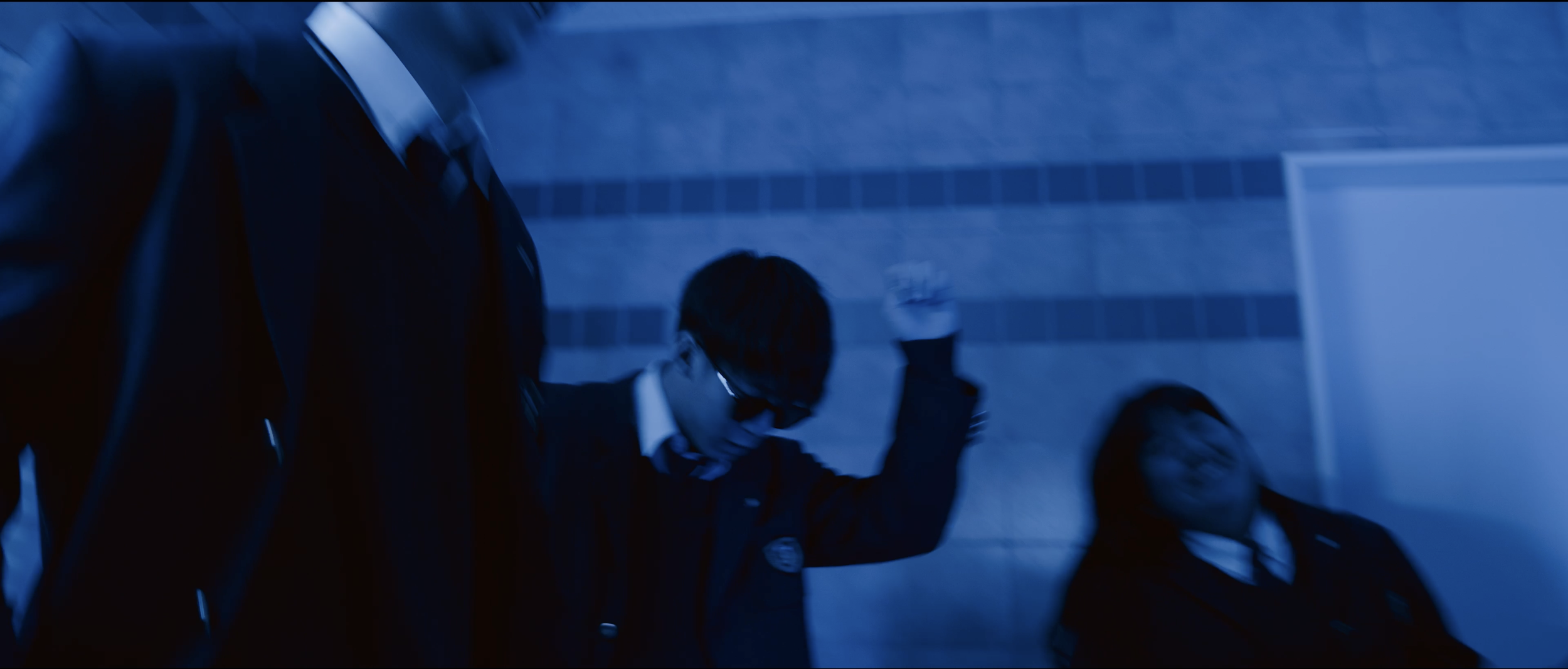 A group of police officers in uniform, standing and talking in an indoor setting with tiled walls, all dressed formally.