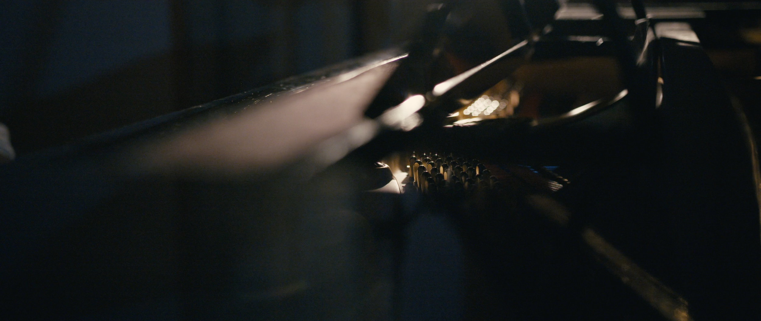 Close-up of the strings inside a grand piano with a warm, soft light illuminating the tuning pins and strings.