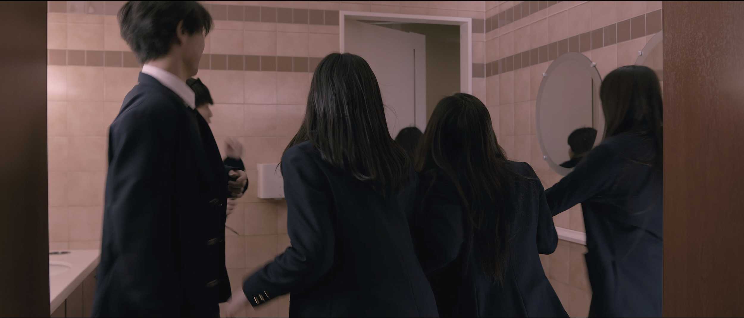 Group of students standing in front of a mirror in a school bathroom.