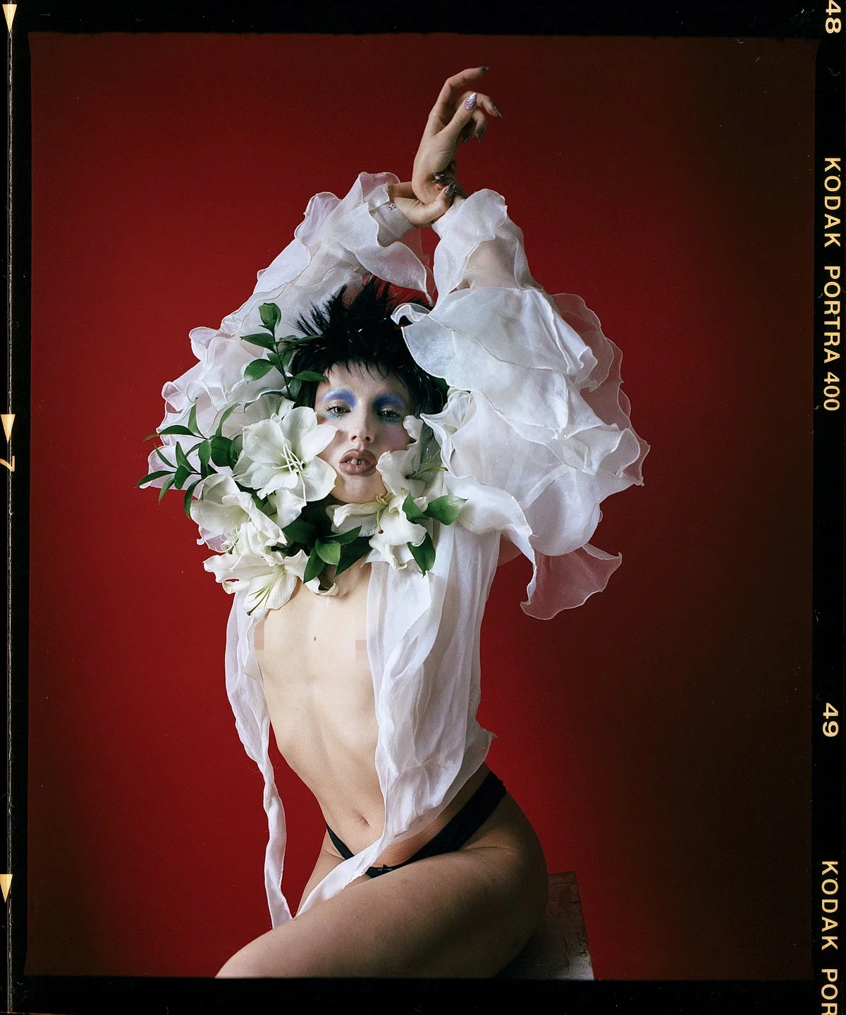 Studio beauty portrait: model framed by white flowers and foliage against red