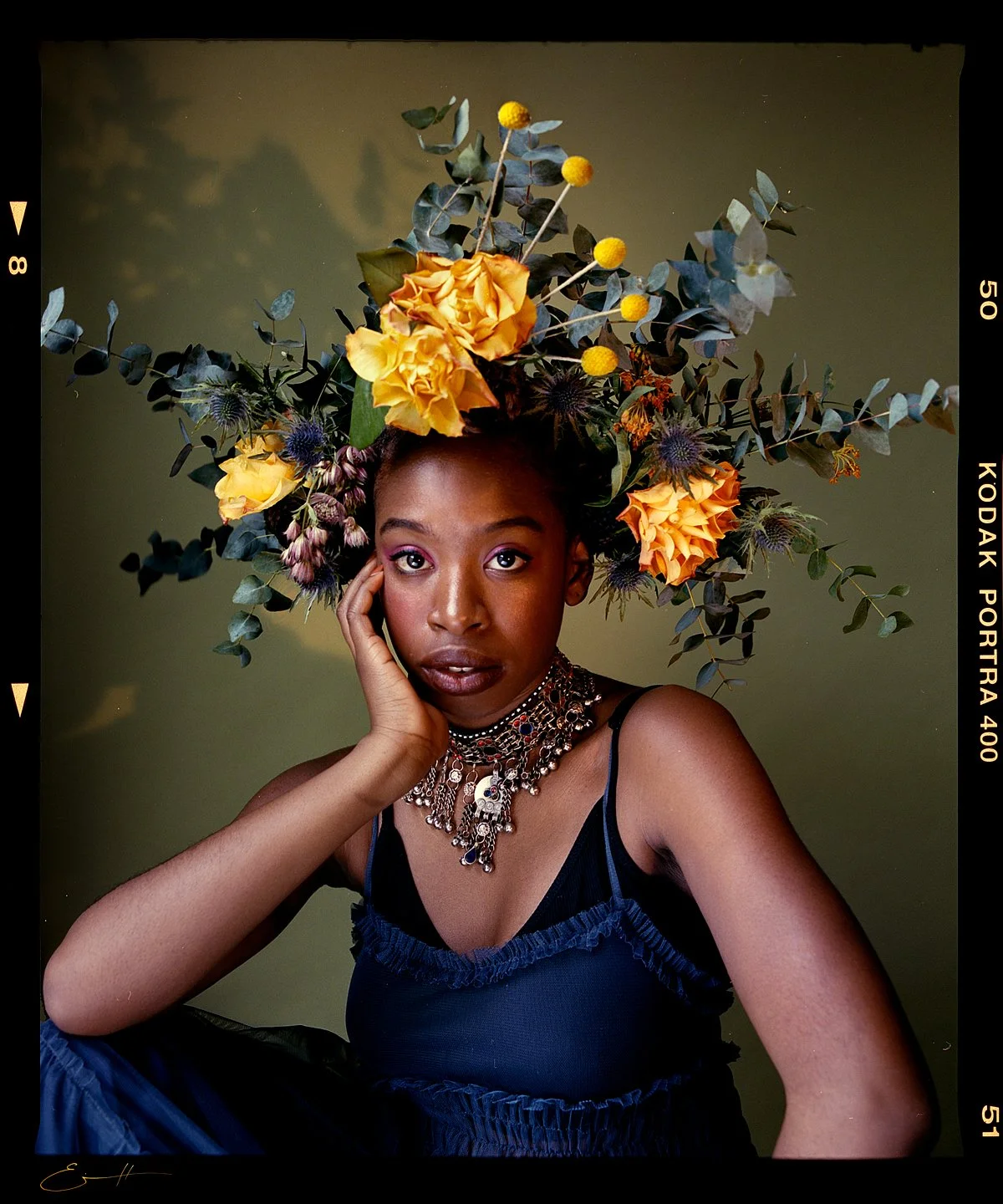 Studio beauty portrait: yellow and purple floral headpiece with a silver necklace