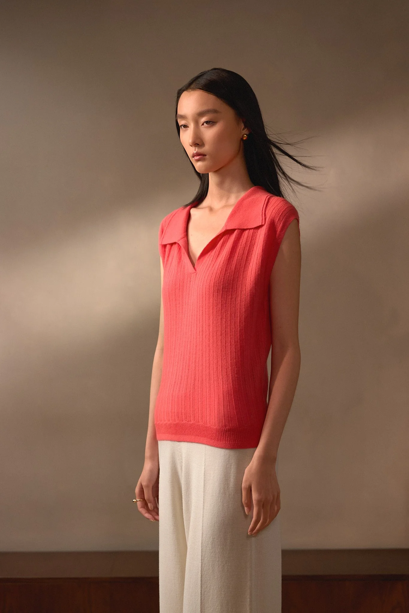 Fashion lookbook: model in a red sleeveless top and pale trousers