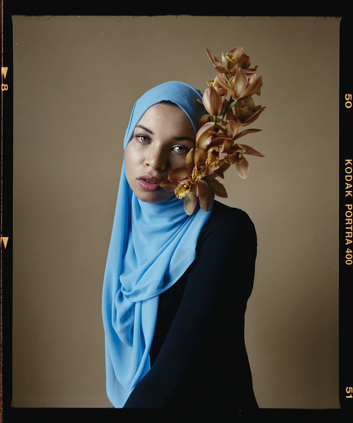 Studio portrait: blue headscarf with an orchid across the face