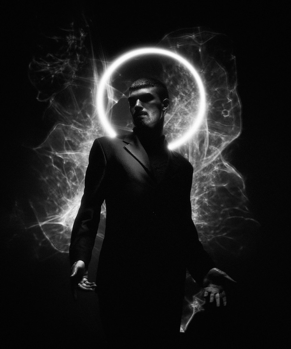 Music portrait: artist in a suit lit by a glowing halo of light