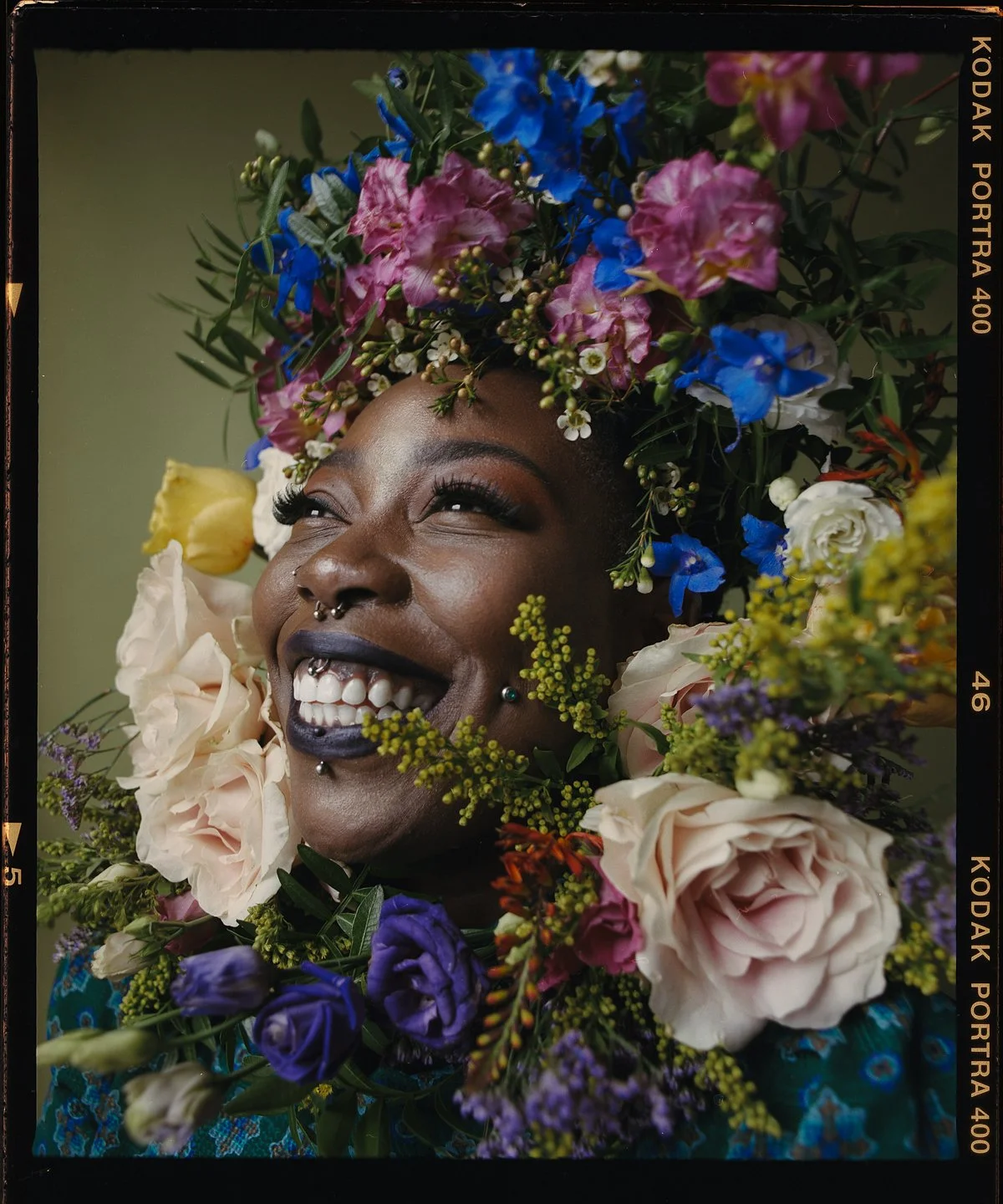 Studio portrait: smiling model surrounded by colourful flowers