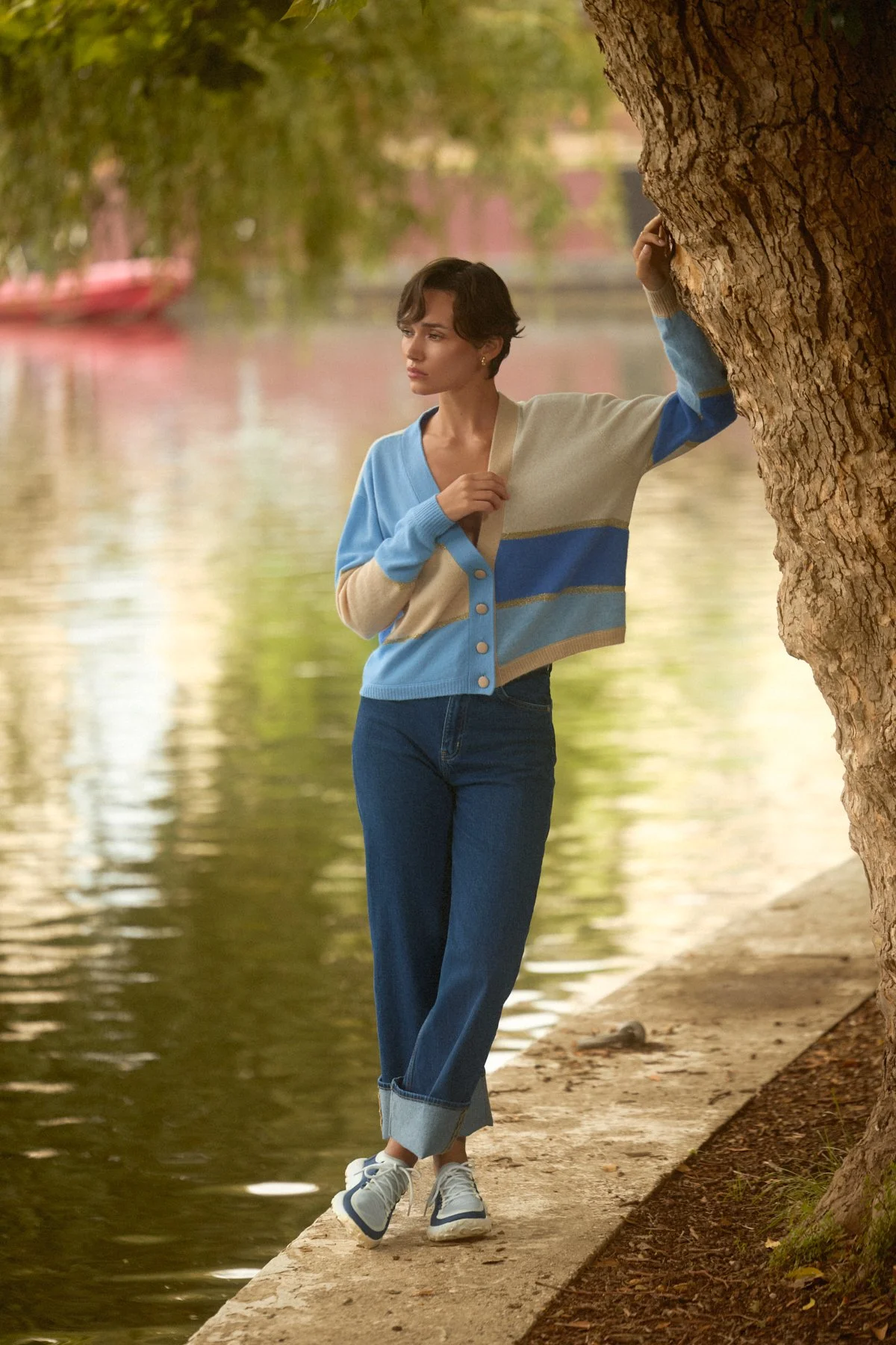 Knitwear lookbook: model leaning against a tree on a riverside path
